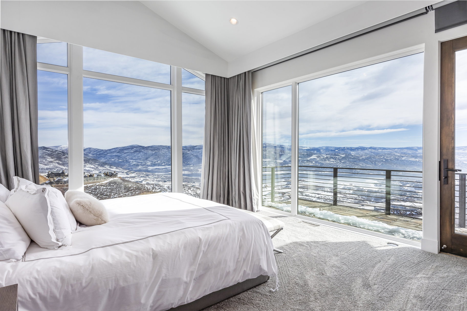 Expansive room featuring floor-to-ceiling windows, a vaulted ceiling, and direct access to an exterior deck