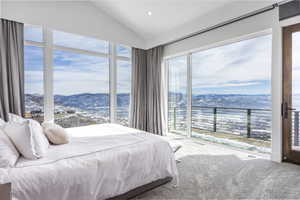 Expansive room featuring floor-to-ceiling windows, a vaulted ceiling, and direct access to an exterior deck