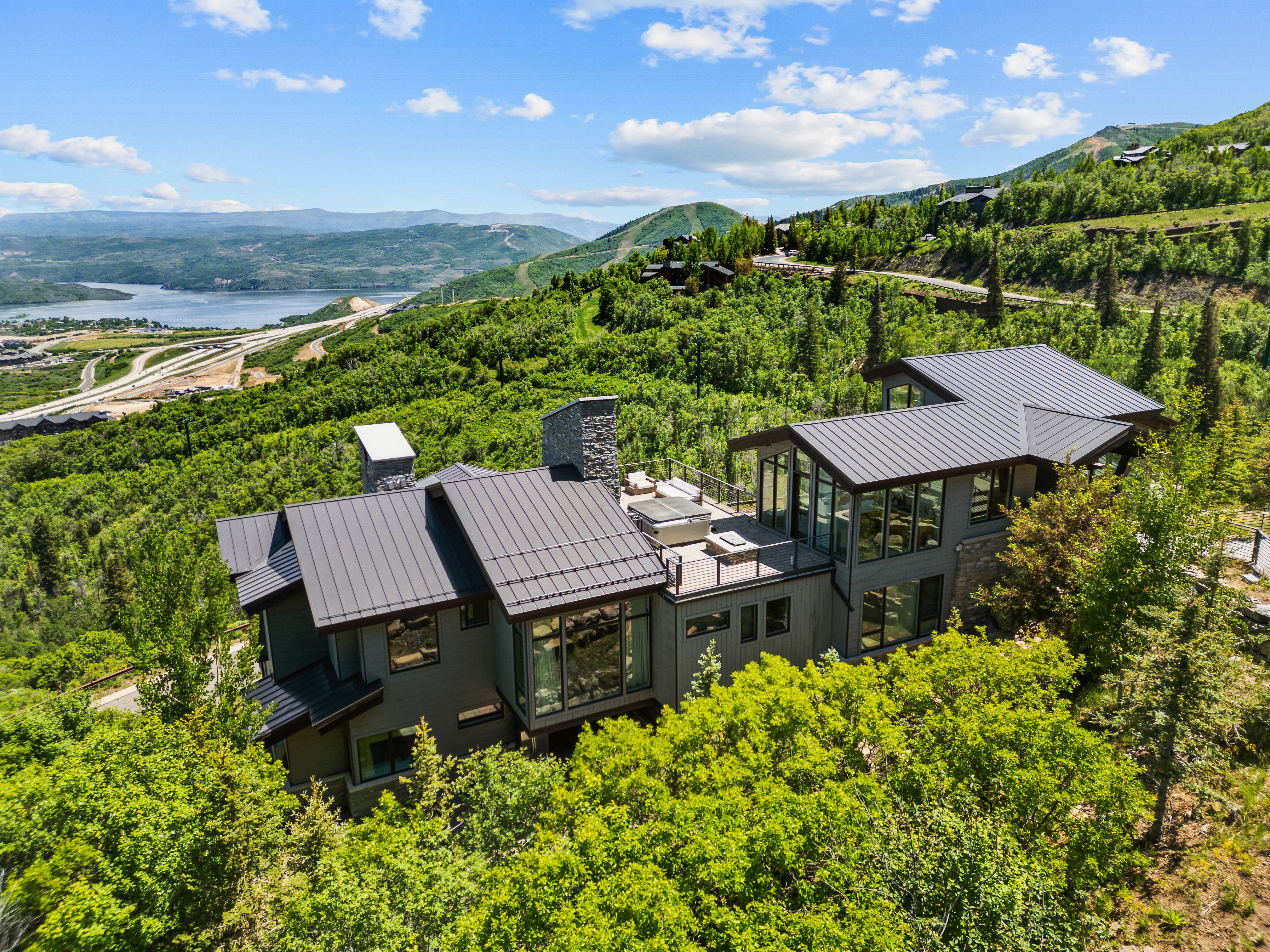 Modern architectural residence featuring multiple levels, a dark metal roof, and extensive window walls