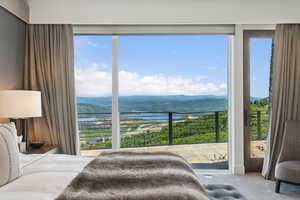 Expansive glass sliding doors open to an outdoor patio with metal railings, showcasing scenic mountain and lake vistas