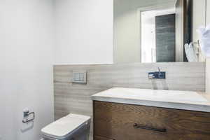 Contemporary bathroom featuring a dark wood-finish vanity with an integrated white sink, a wall-mounted faucet, and a large frameless mirror
