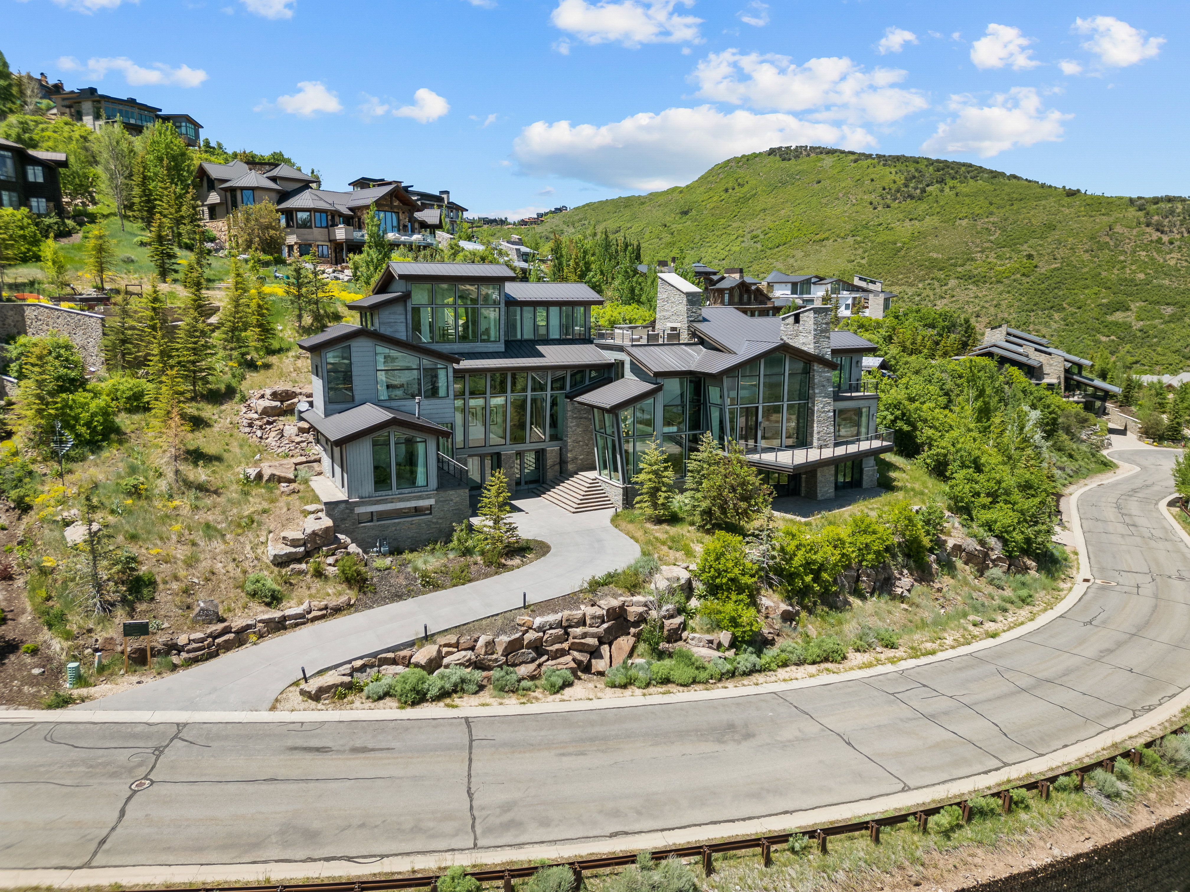 Contemporary multi-level residence featuring extensive floor-to-ceiling windows, stone accents, and multiple balconies
