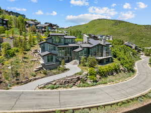 Contemporary multi-level residence featuring extensive floor-to-ceiling windows, stone accents, and multiple balconies