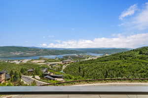 Expansive mountain and lake scenery with a prominent body of water, rolling hills, and a clear blue sky