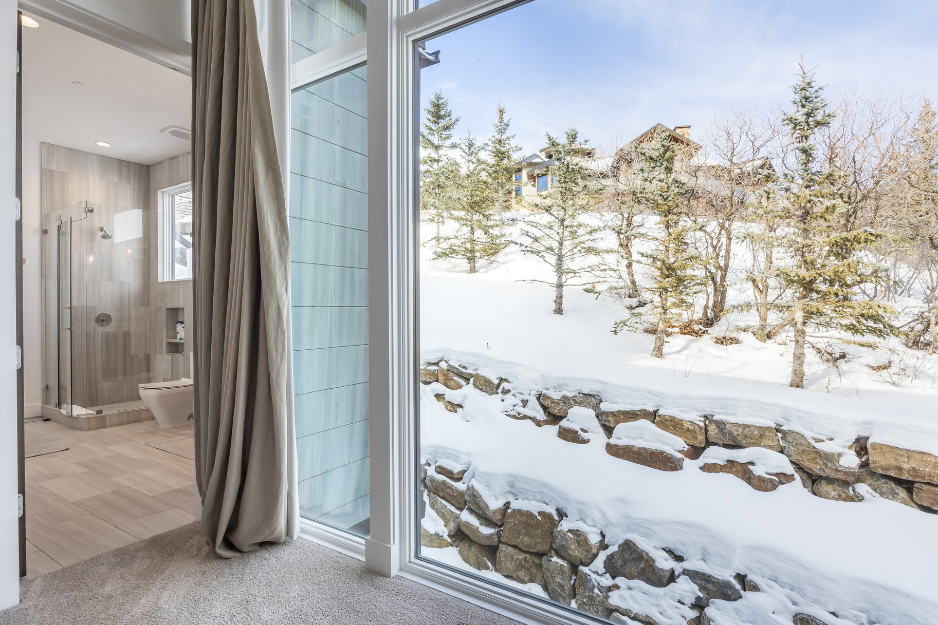 Expansive window overlooking a snow-covered landscape with mature evergreens