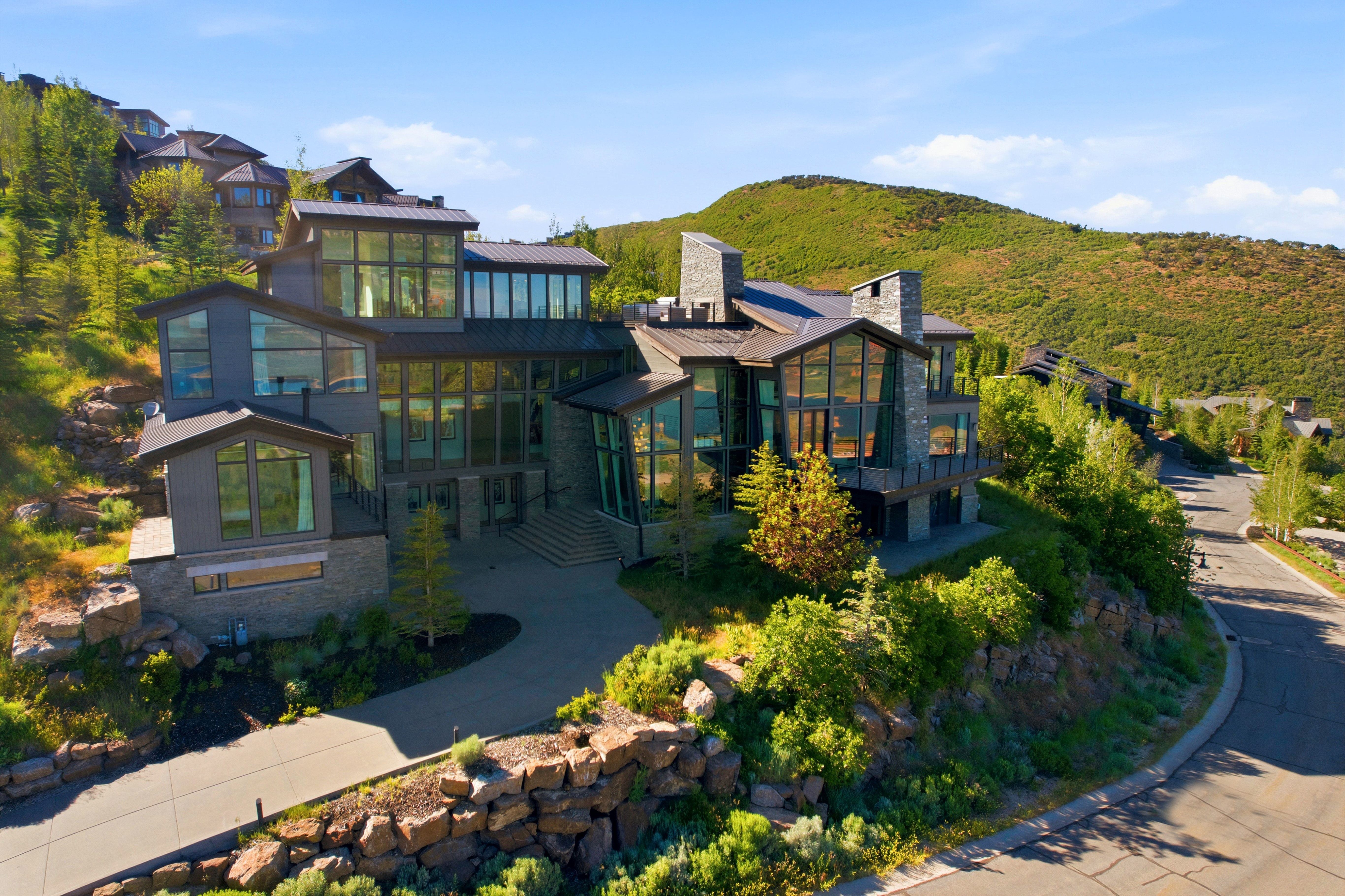 Multi-level modern residence featuring extensive glazing, stone accents, and varied rooflines