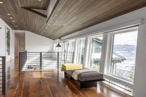 Open-concept upper level featuring rich wood-finish flooring, a sloped wood-paneled ceiling with recessed lighting, and a contemporary metal railing system