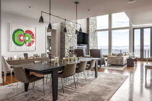 Open-concept interior featuring wood-finish flooring, a stone accent wall, and expansive windows