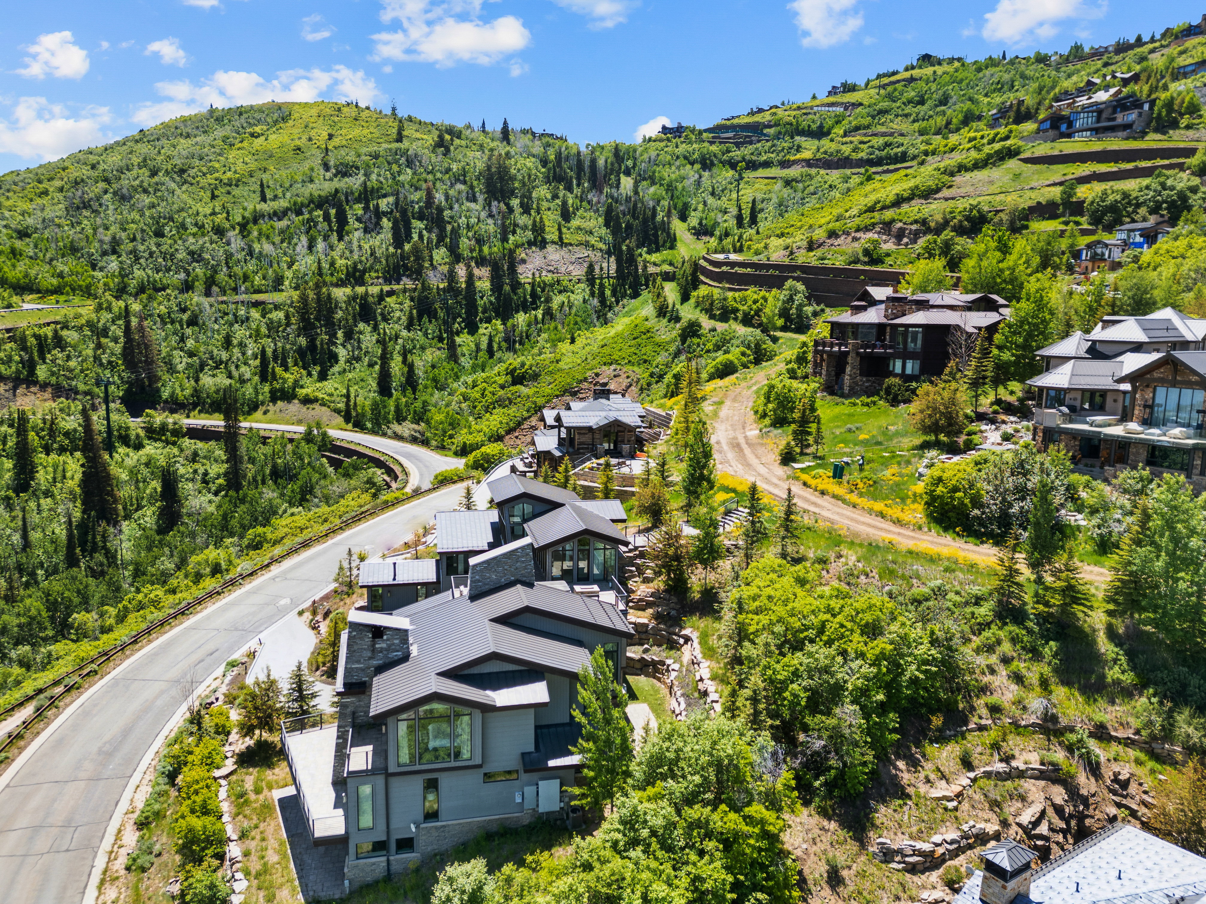 Modern mountain architecture featuring multiple structures with dark grey siding and stone accents