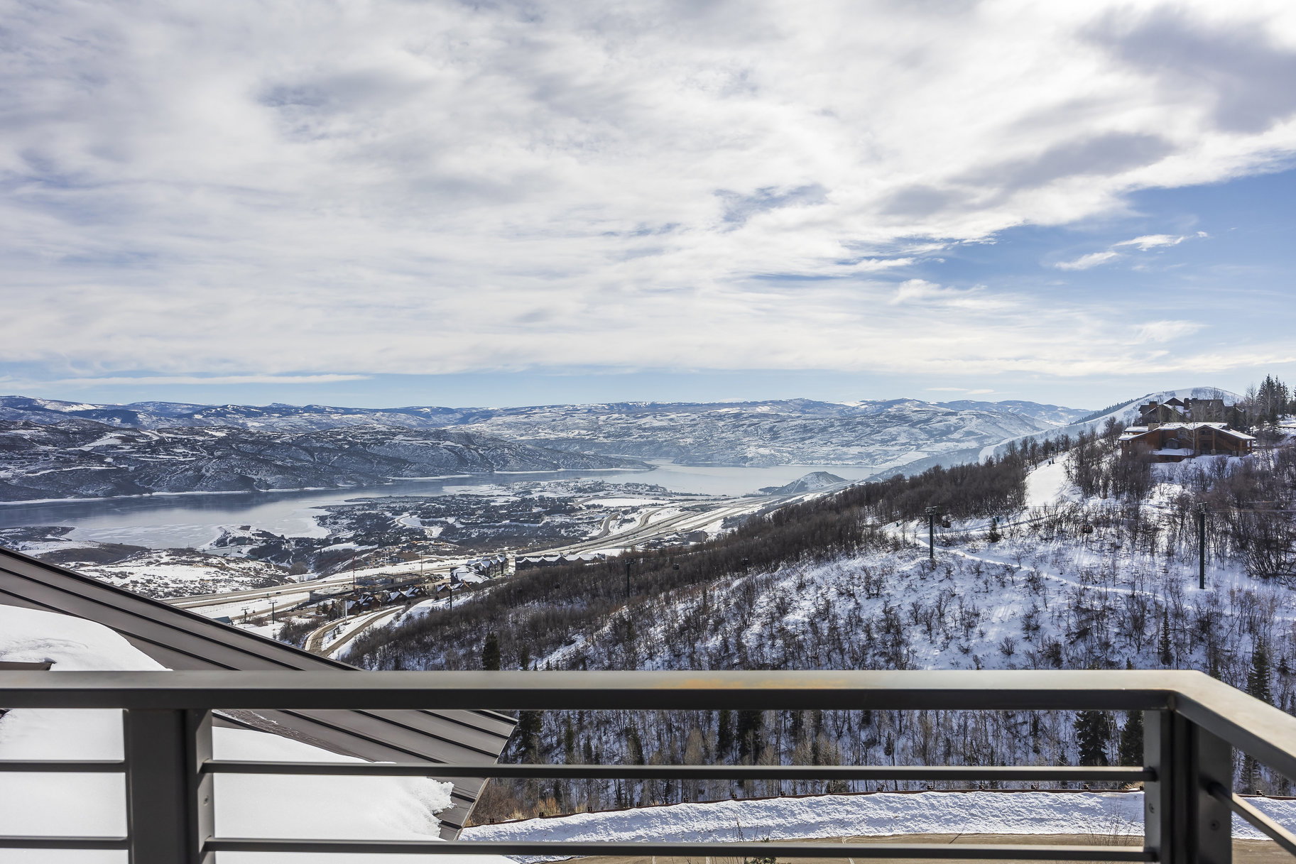 Expansive mountain and lake scenery from a contemporary balcony featuring metal railings