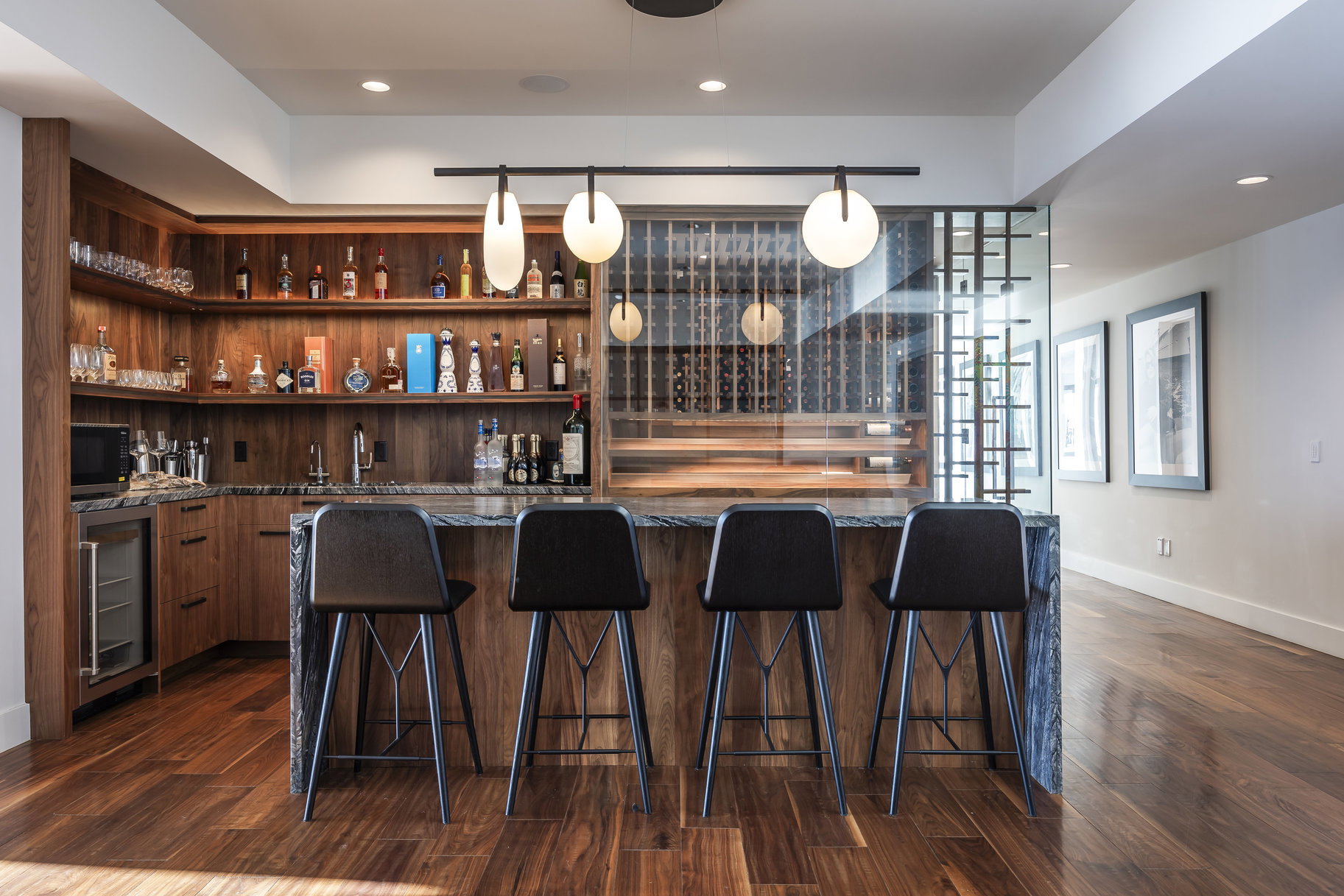 Custom bar area featuring wood-finish cabinetry and open shelving, a built-in beverage cooler, and a stone countertop