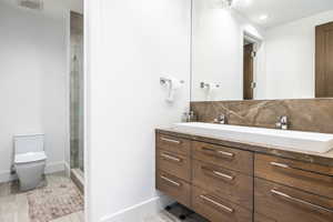Contemporary bathroom featuring a floating wood-finish vanity with ample storage, an integrated dual sink, and a stone countertop with a matching backsplash