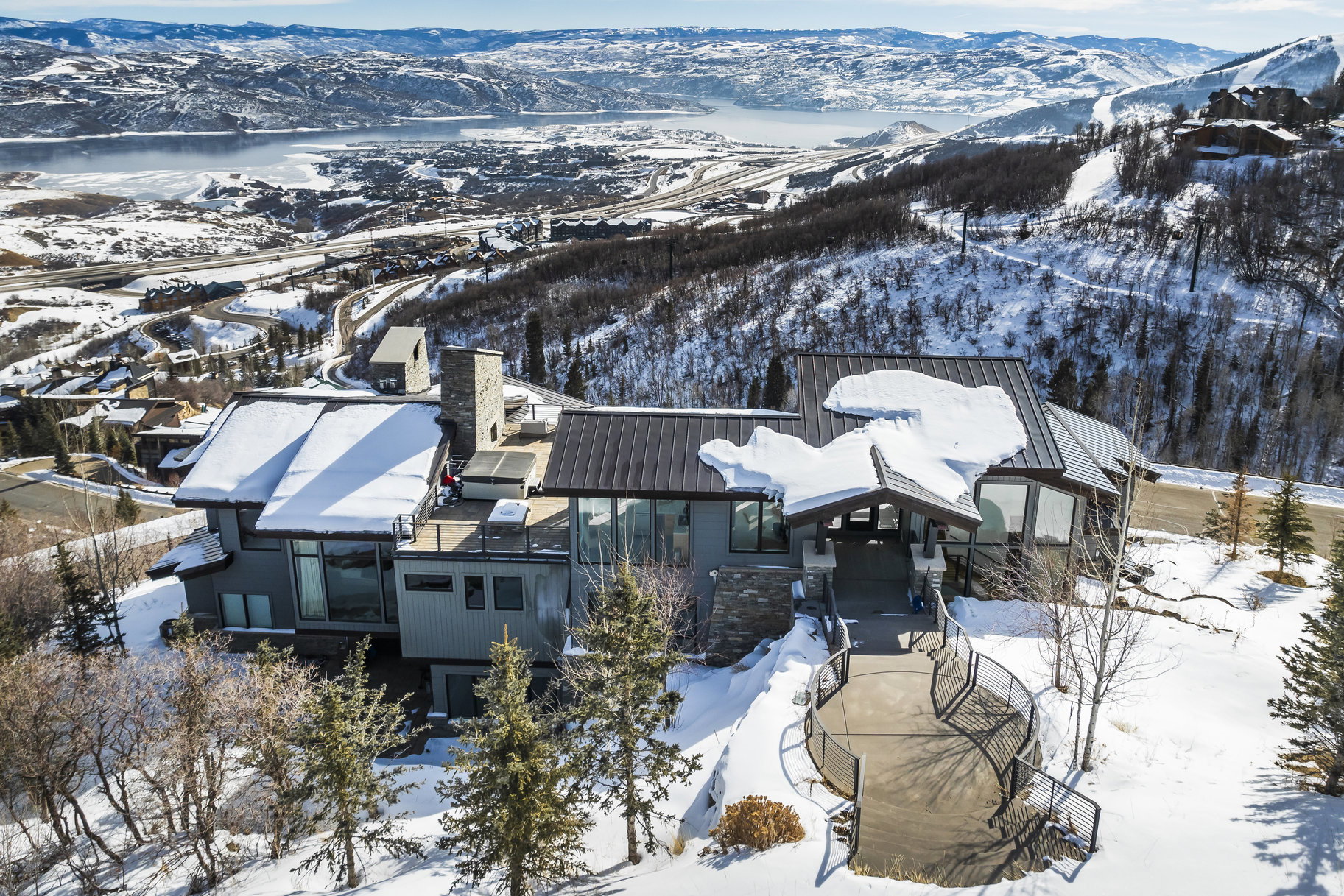 Contemporary mountain residence featuring a multi-level design, multiple outdoor terraces, large windows, and a metal roof