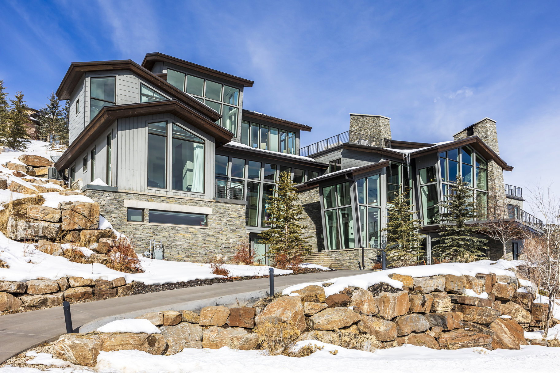 Contemporary multi-level residence featuring extensive stone cladding and vertical siding
