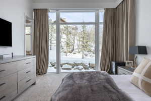 Floor-to-ceiling sliding glass doors open to an outdoor area featuring natural rock formations and winter foliage
