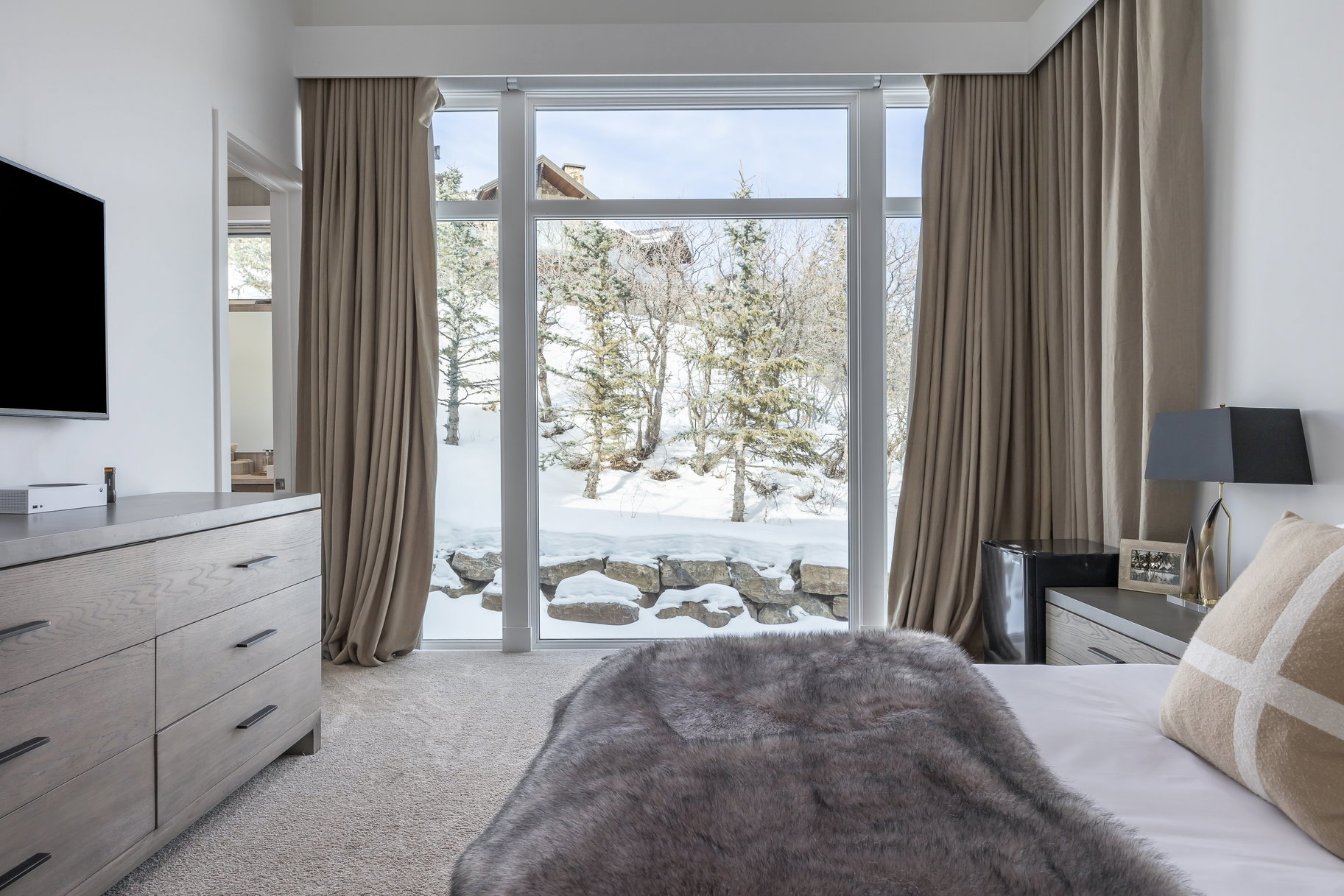 Floor-to-ceiling sliding glass doors open to an outdoor area featuring natural rock formations and trees