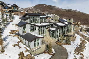 Contemporary multi-level residence featuring extensive glass facades, stone accents, and dark metal roofing