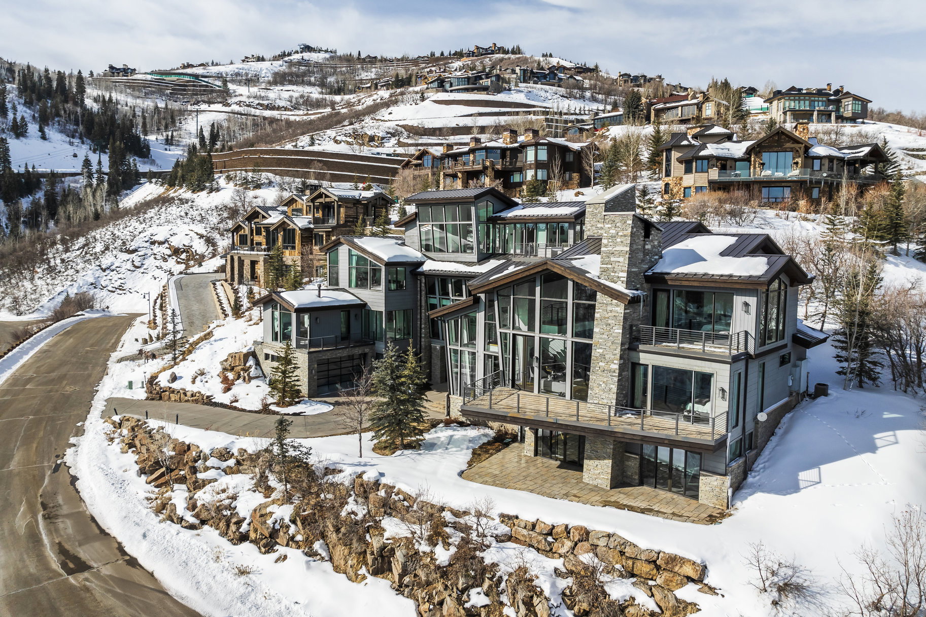 Multi-level modern residence featuring extensive glazing, stone veneer, and multiple balconies