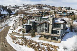 Multi-level modern residence featuring extensive glazing, stone veneer, and multiple balconies