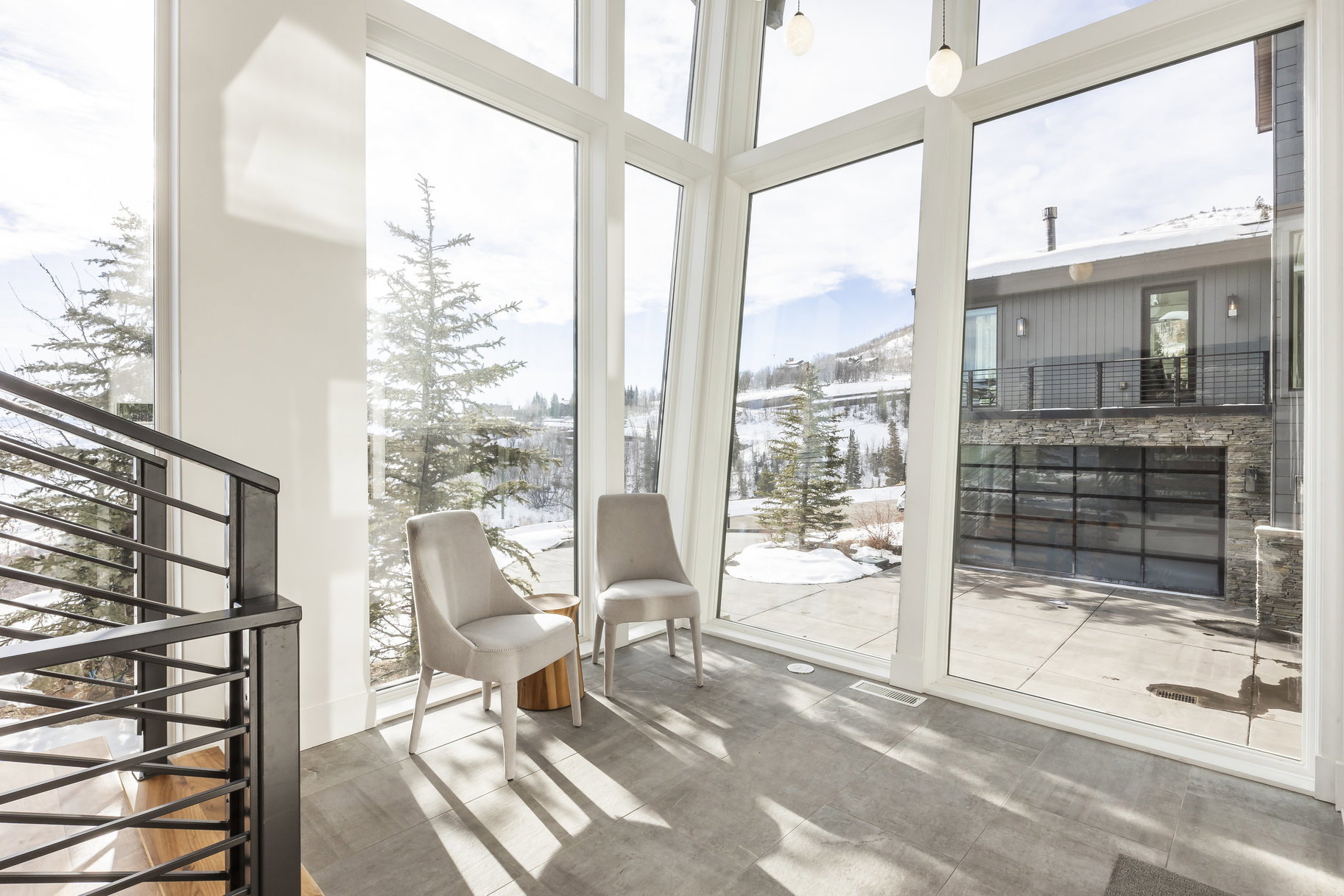 Expansive floor-to-ceiling windows with white framing, offering broad outdoor scenery