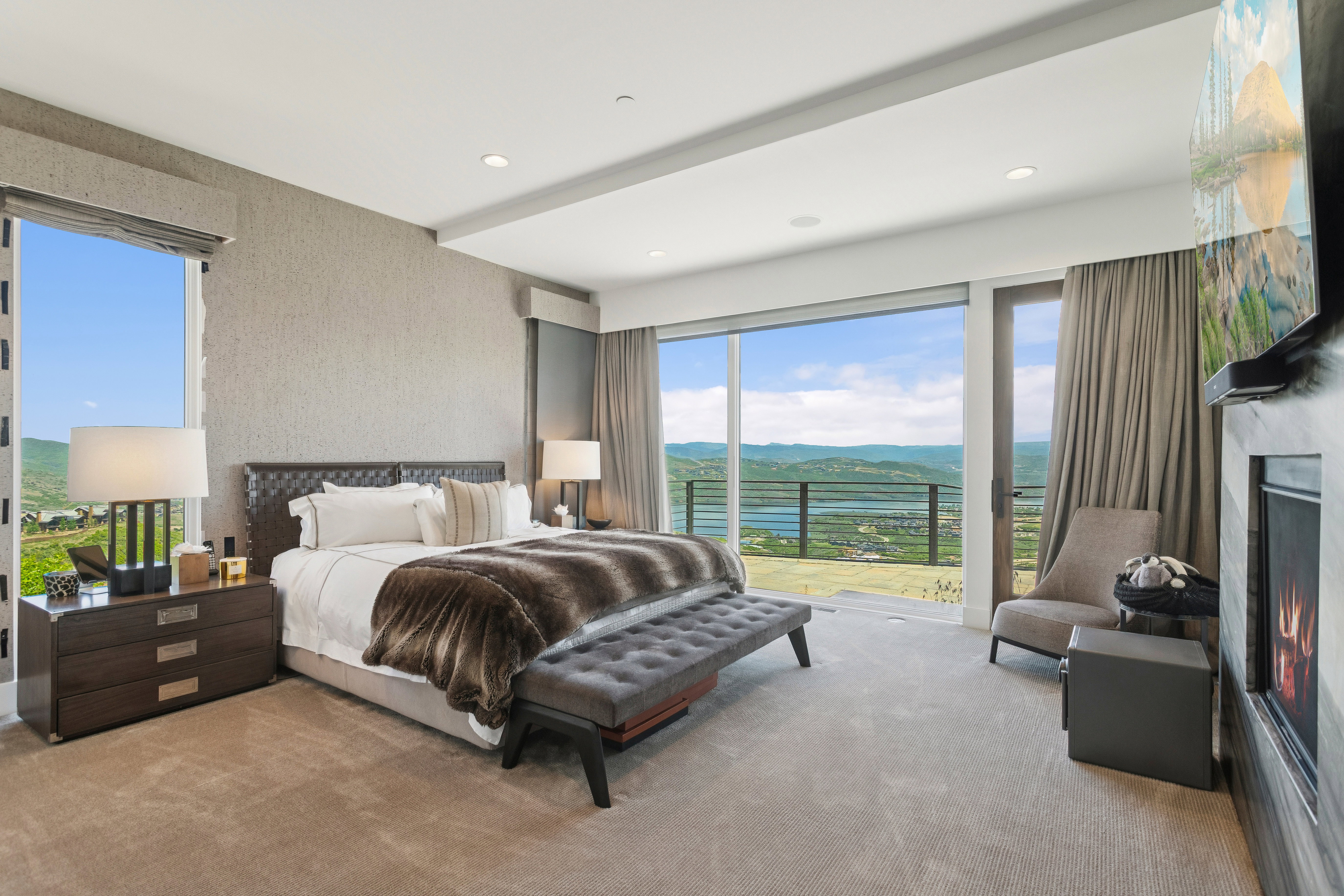 Bedroom with expansive sliding glass doors opening to a scenic mountain and lake backdrop