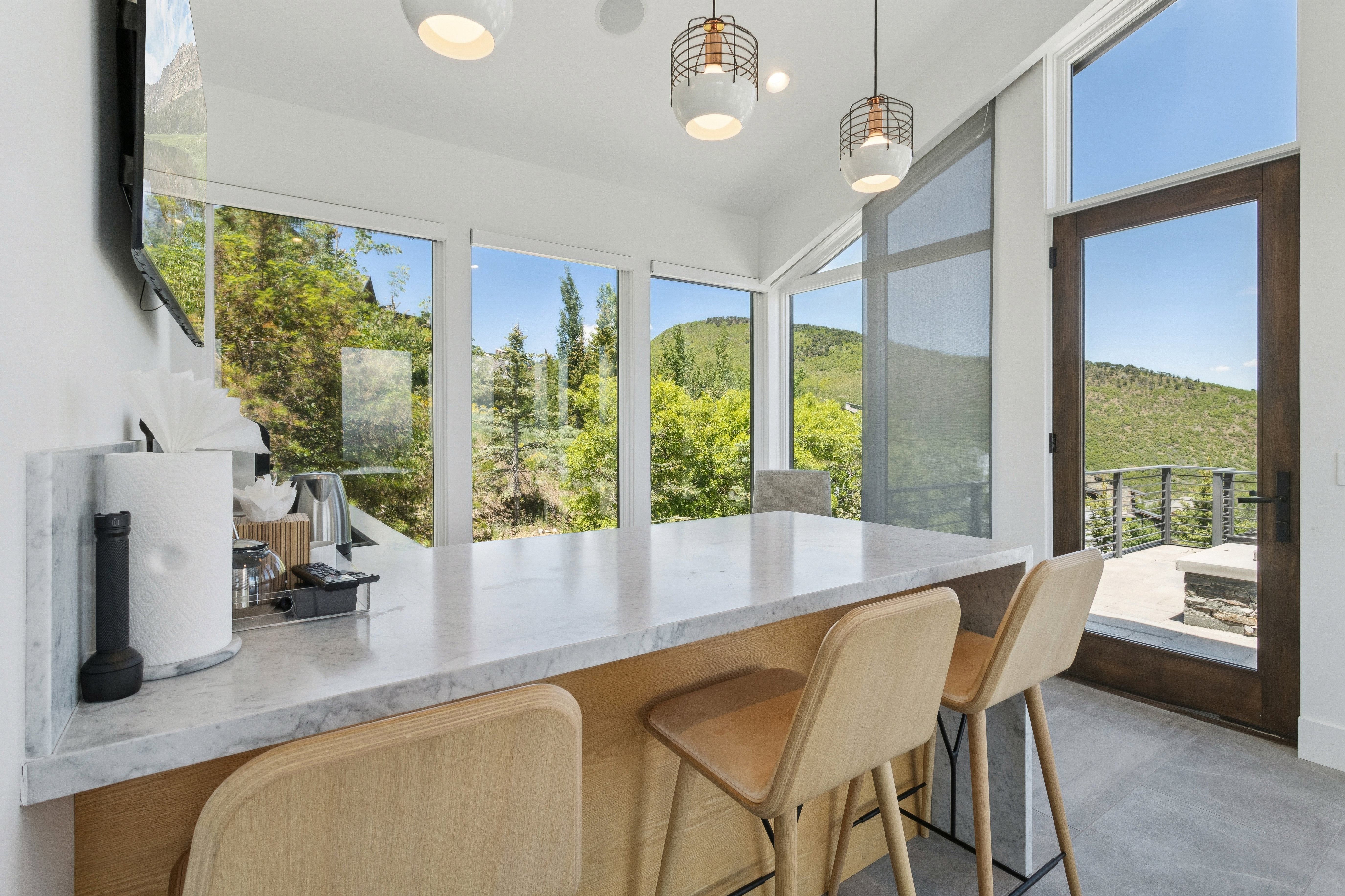 Kitchen island featuring a light-toned stone countertop, integrated wood-finish cabinetry, and contemporary pendant lighting