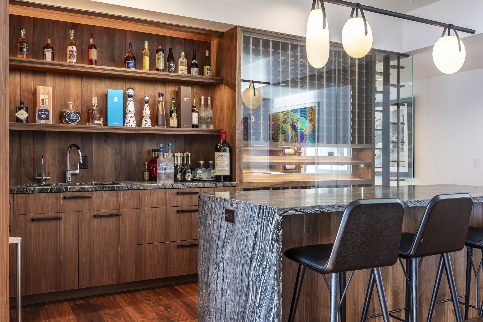 Integrated wet bar featuring a built-in sink, dark stone countertop, and open shelving