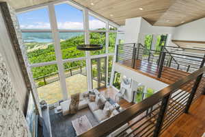 Vaulted great room with expansive window walls, wood-finish ceiling, stone fireplace surround, and multi-level living areas