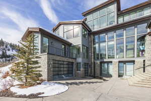 Modern multi-level residence featuring extensive glass window panels and stone accents