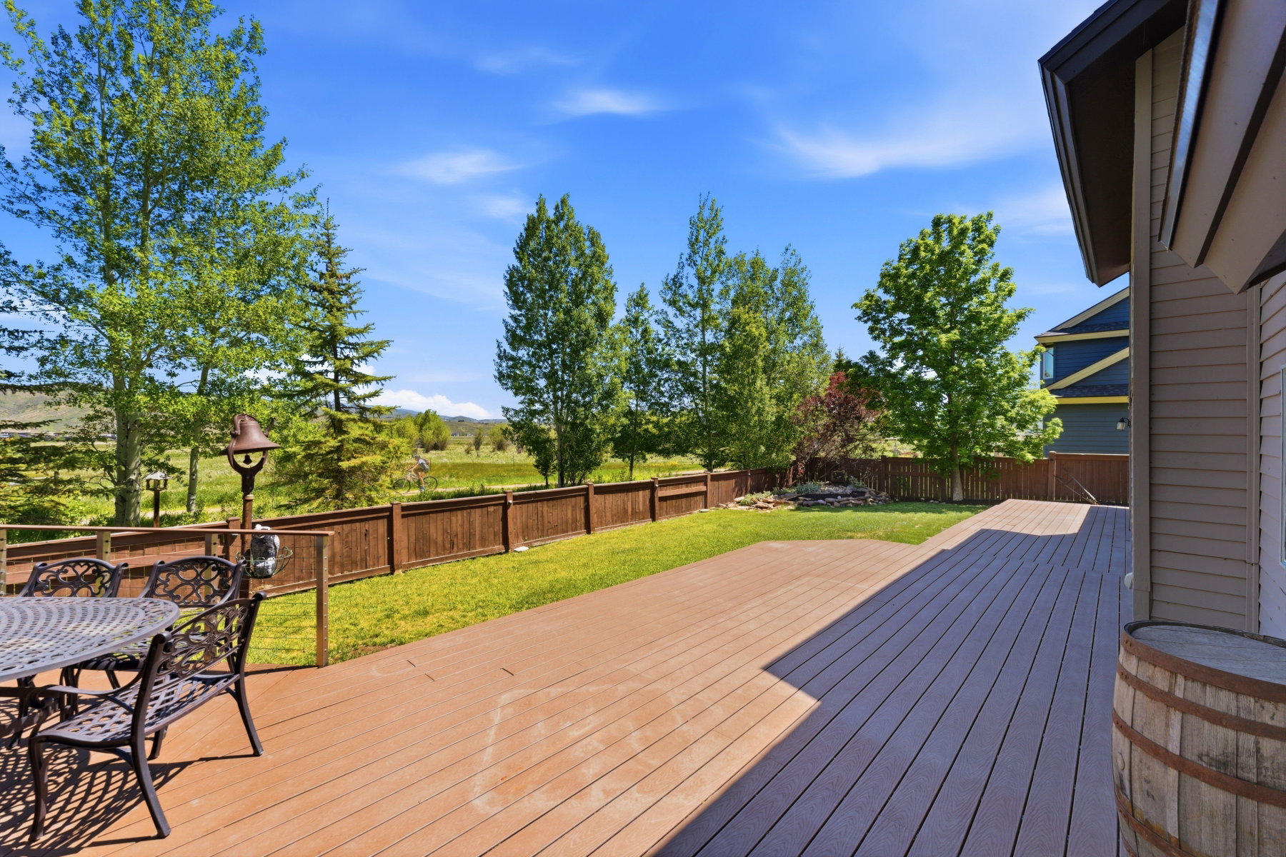 Expansive backyard featuring a multi-level deck, manicured lawn, and a wood privacy fence