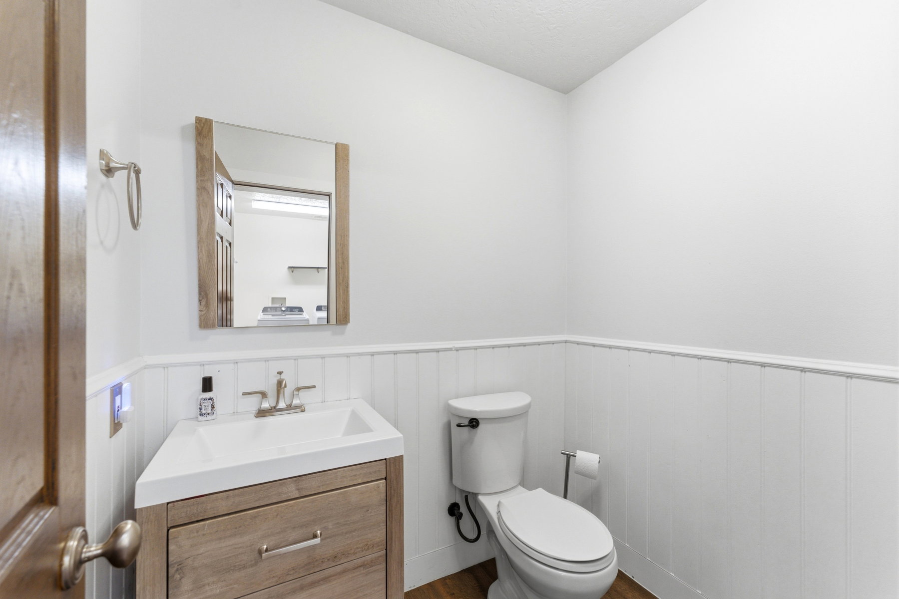 Bathroom featuring a wood-finish vanity with an integrated sink, brushed nickel faucet, and a coordinating framed mirror