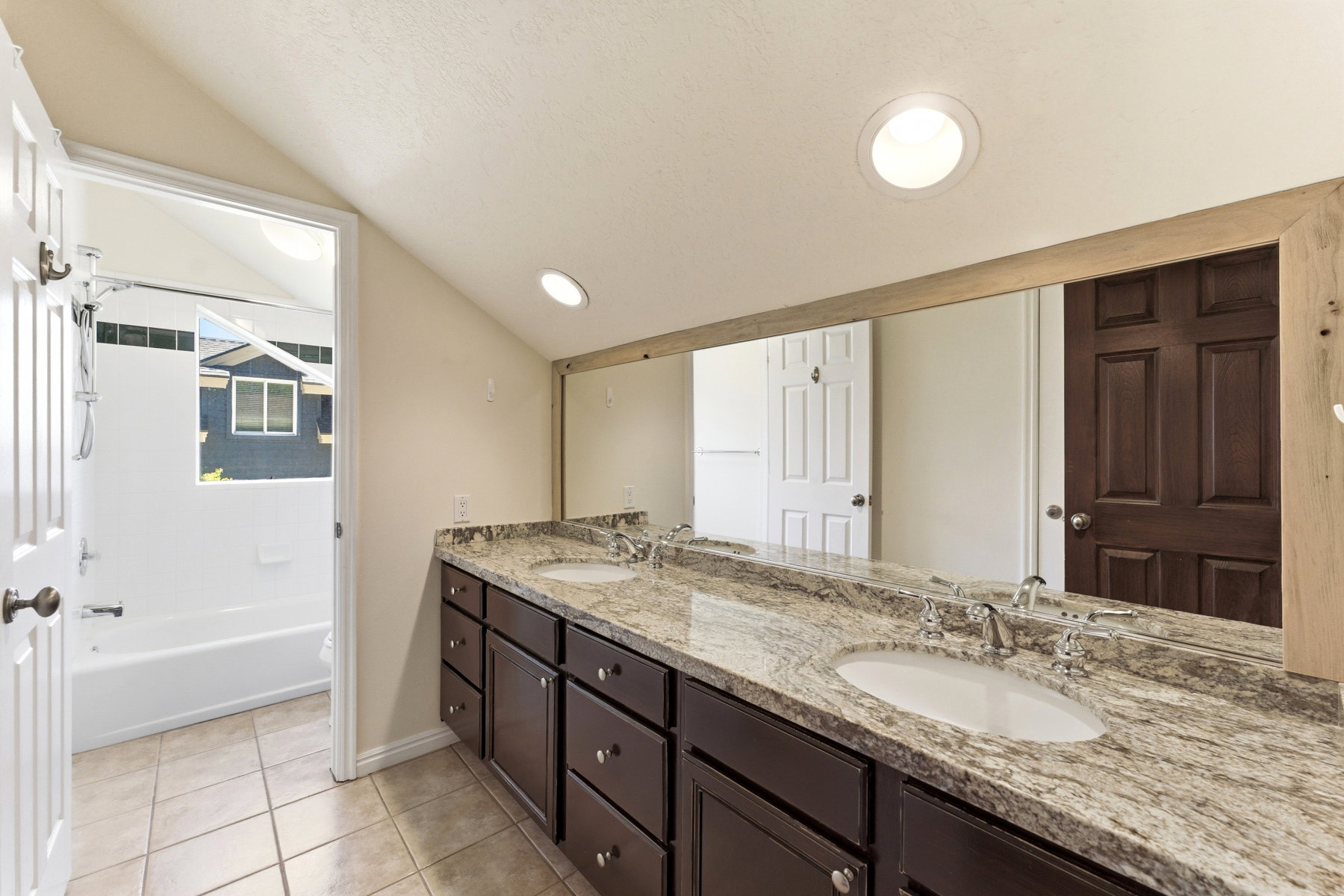 Vanity featuring dual undermount sinks, granite countertop, and dark wood cabinetry