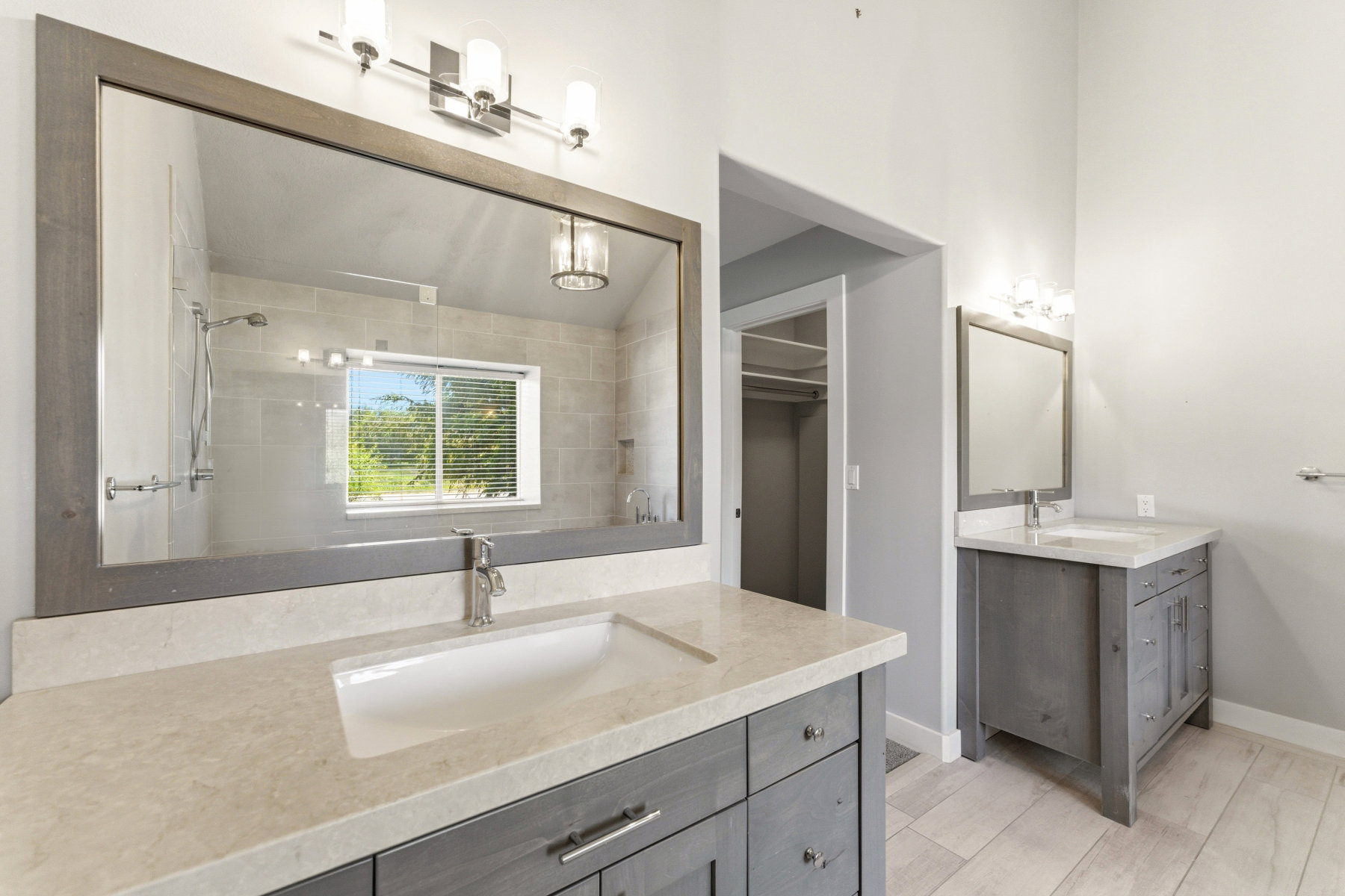 Dual vanity bathroom featuring light-toned wood-finish flooring
