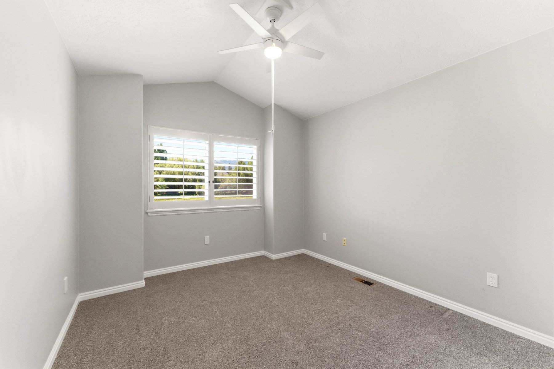 Room with light gray walls, gray carpet, and white baseboards