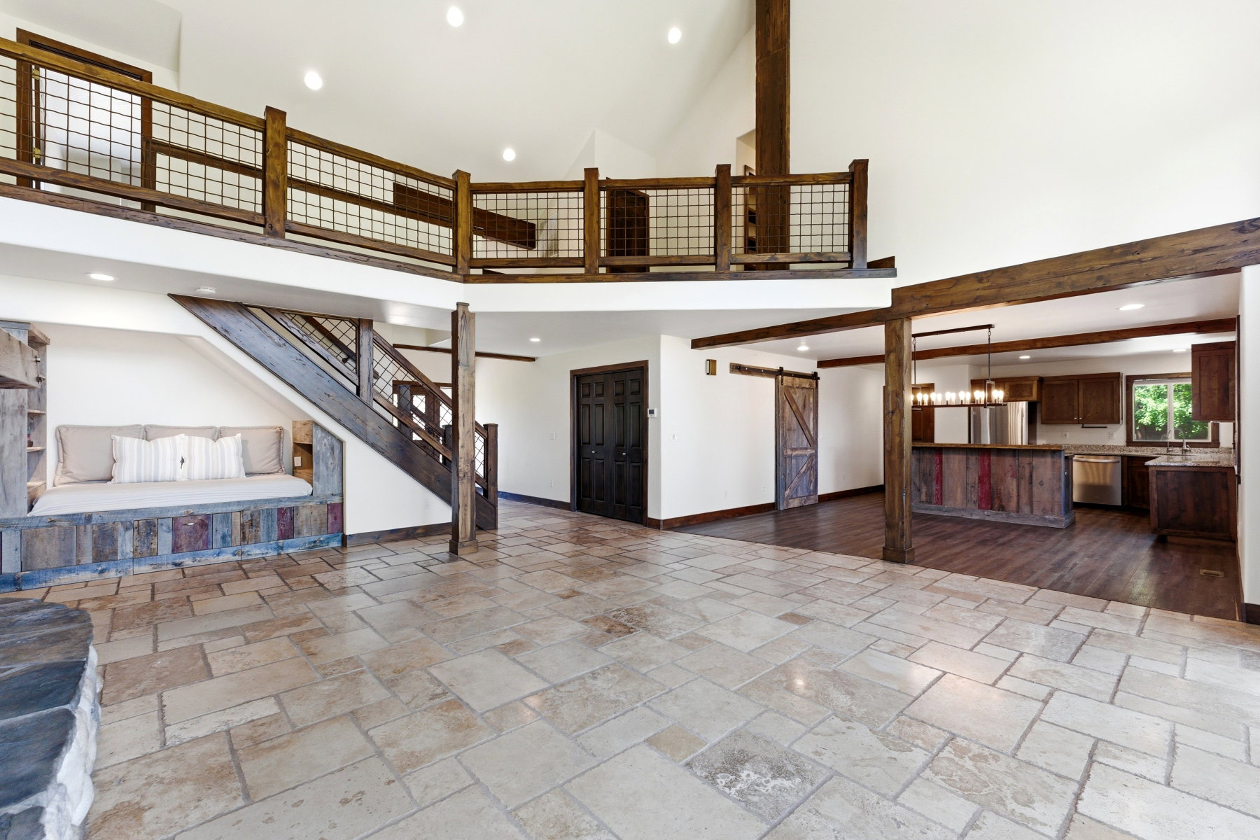 Vaulted ceilings with exposed wood beams, a stone tile floor, and a built-in window seat