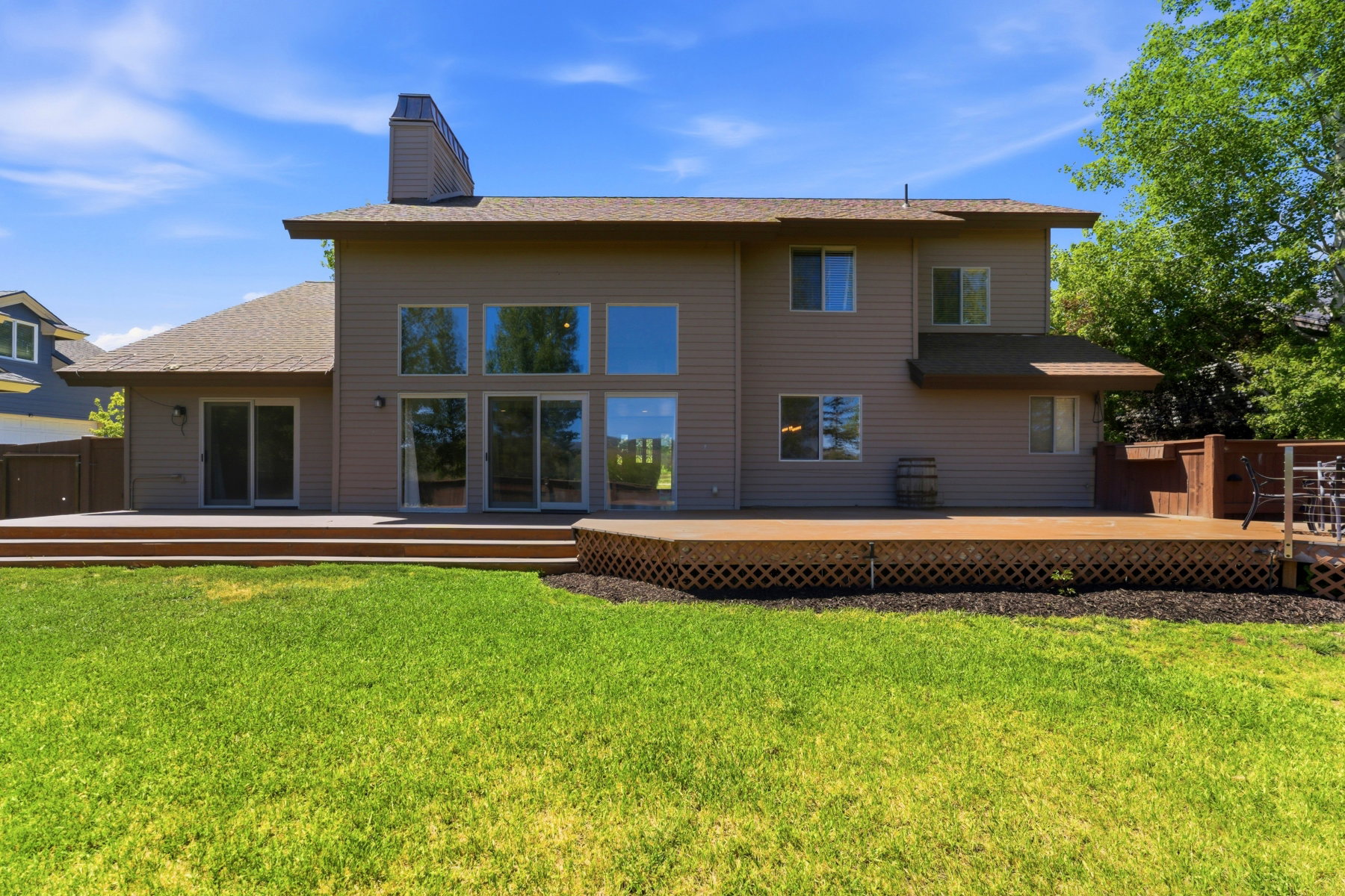 Expansive backyard featuring a large wood deck with lattice skirting