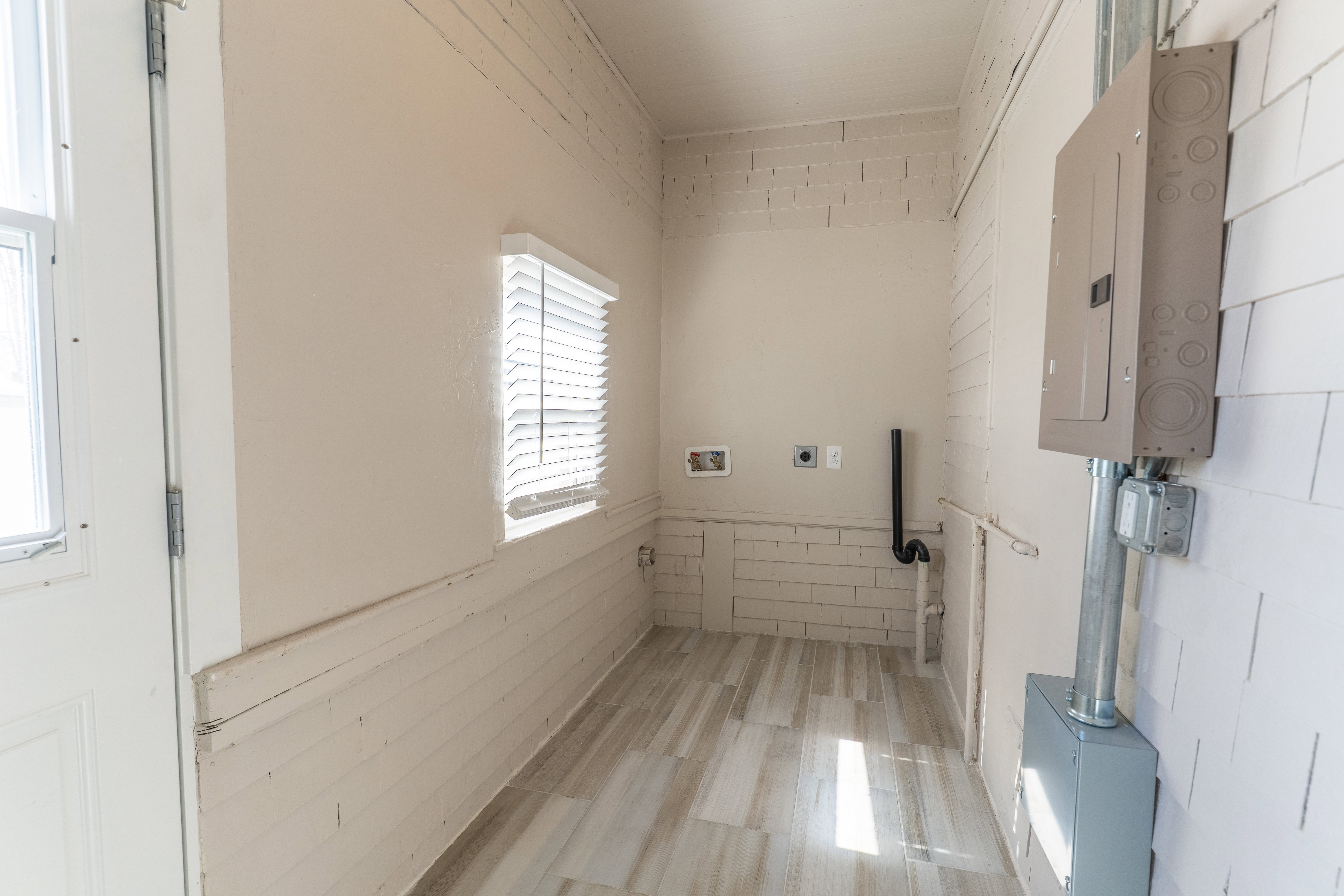 Utility room featuring wood-finish flooring, a window with blinds, and exposed electrical panels