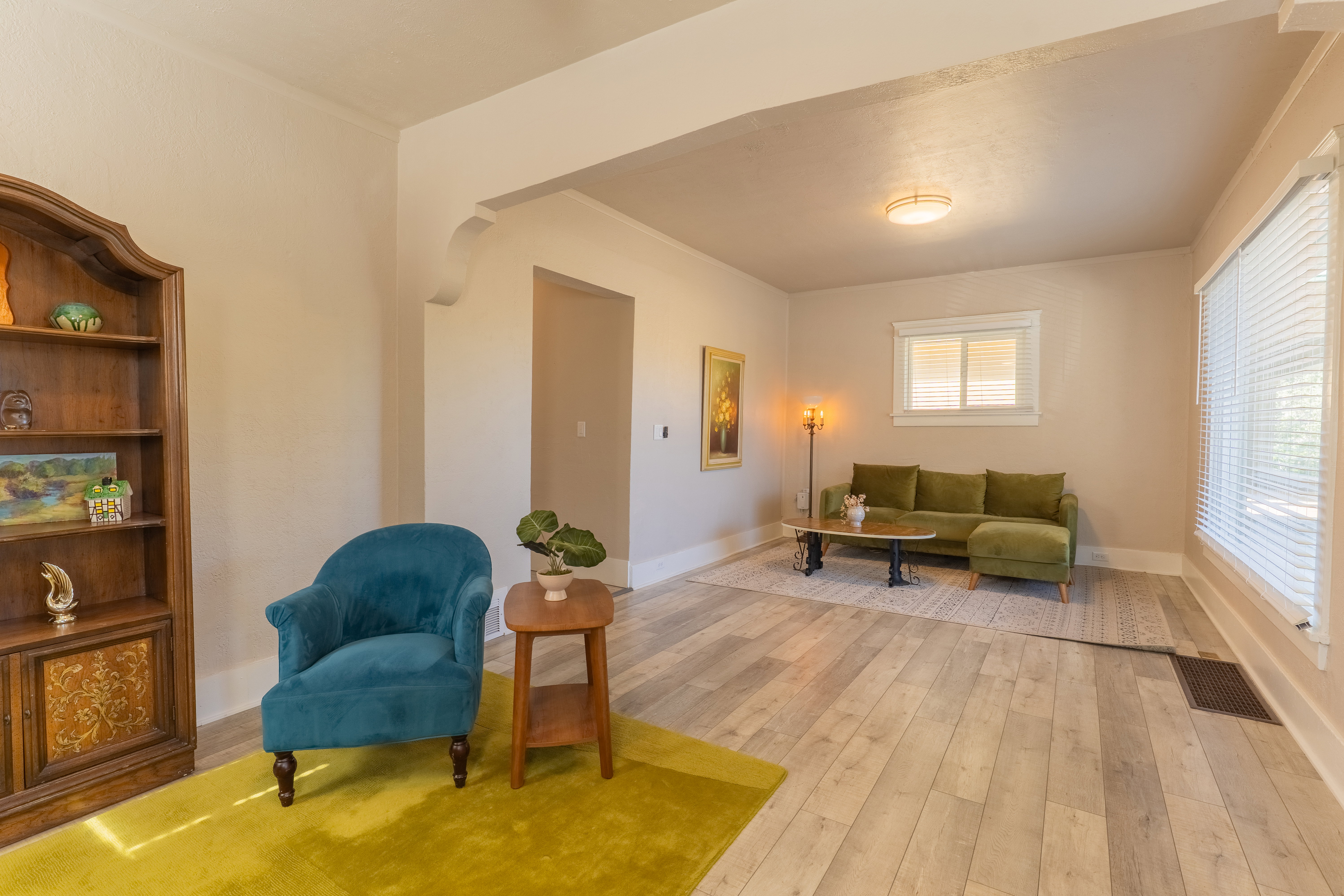 Light-toned wood-finish flooring extends throughout this open living space, featuring neutral wall tones and white trim