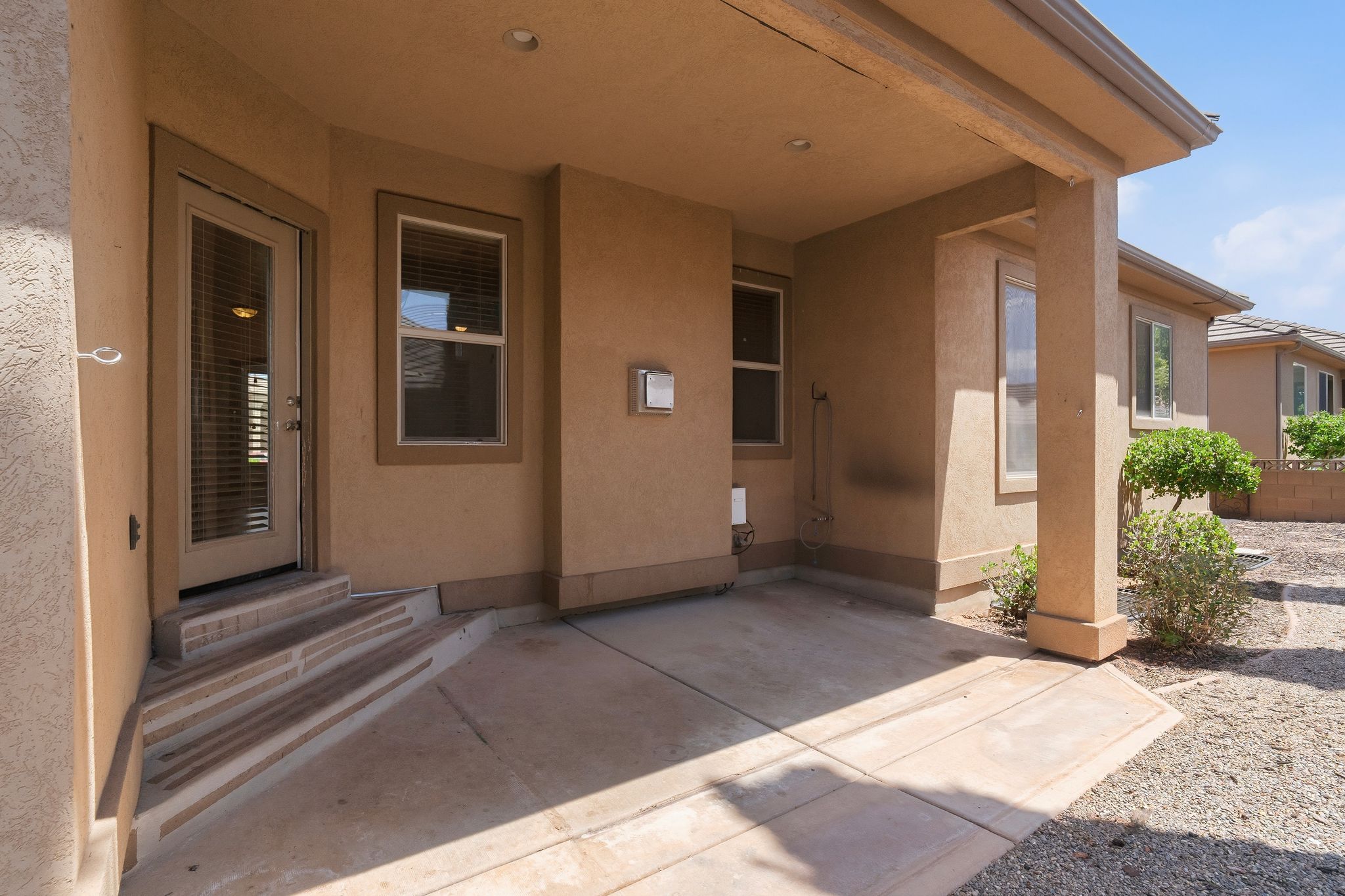 Covered patio featuring an extended concrete slab, stucco exterior, and dual-pane windows