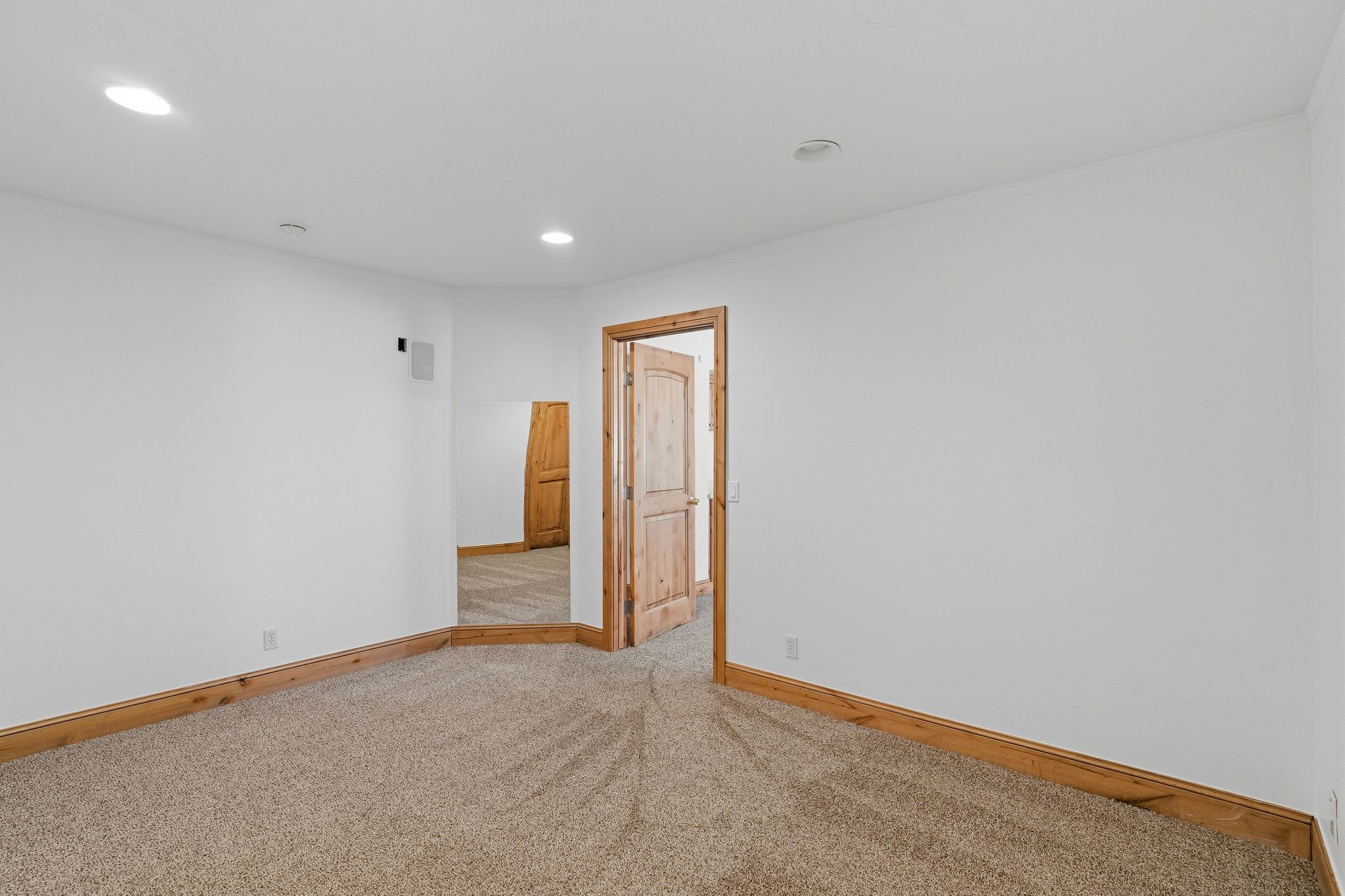 Carpeted interior space featuring white walls and natural wood-finish baseboards