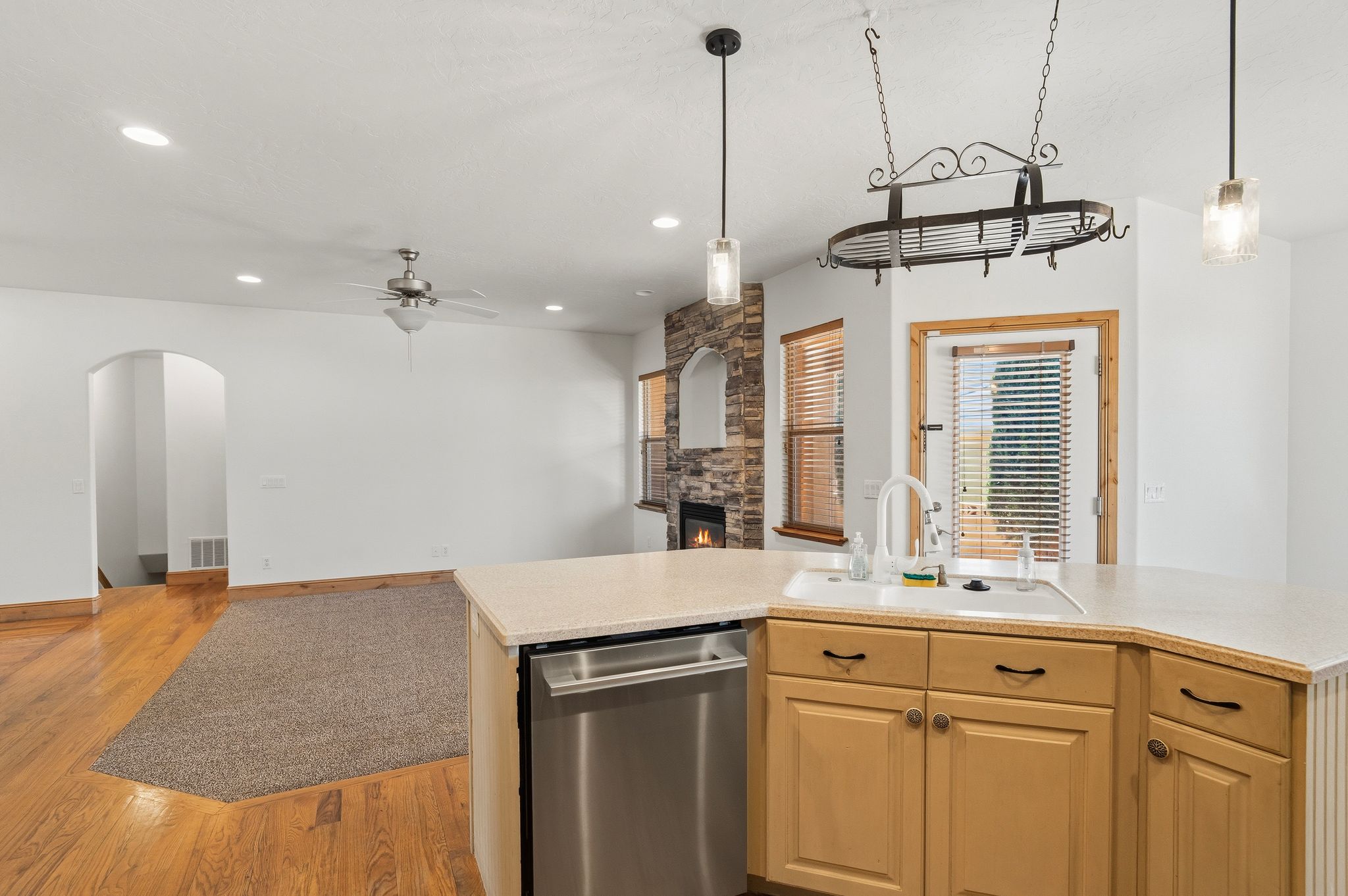 Kitchen island with light-toned cabinetry, stainless steel dishwasher, and a white basin sink