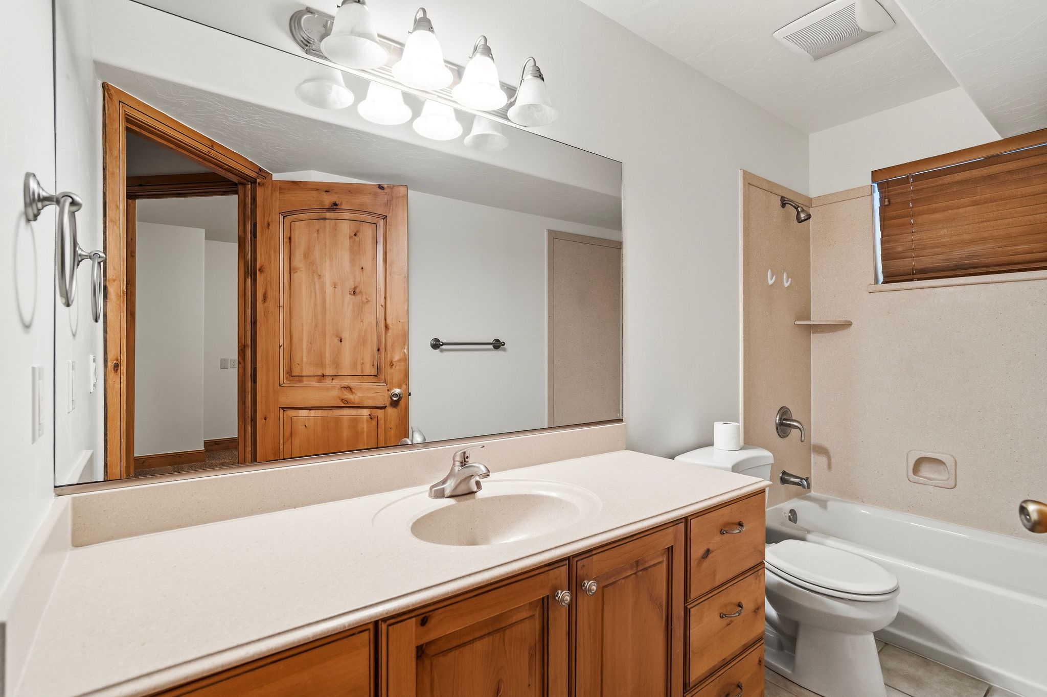 Bathroom featuring a single vanity with wood cabinetry, an integrated sink, and a large mirror