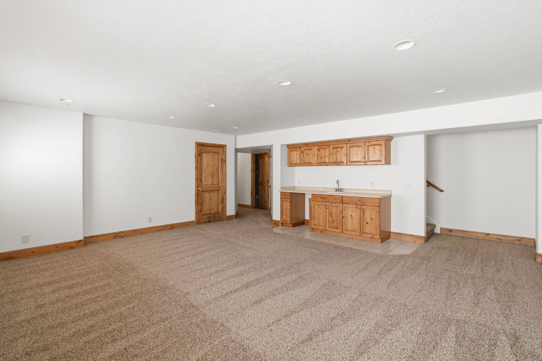 Expansive room featuring light brown carpeting and recessed lighting