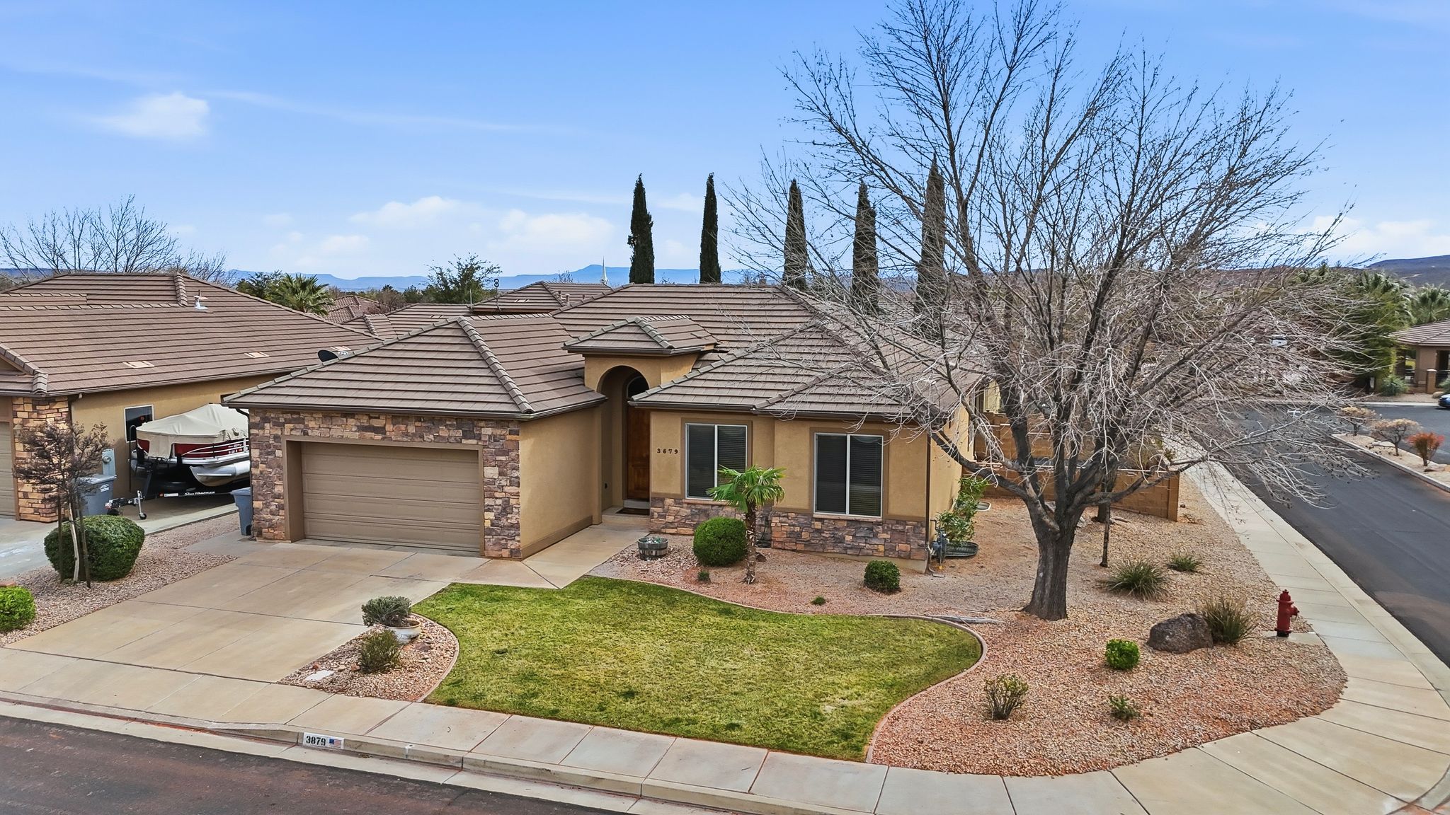 Single-story residence featuring a tile roof, stucco exterior with stone accents, and an attached two-car garage
