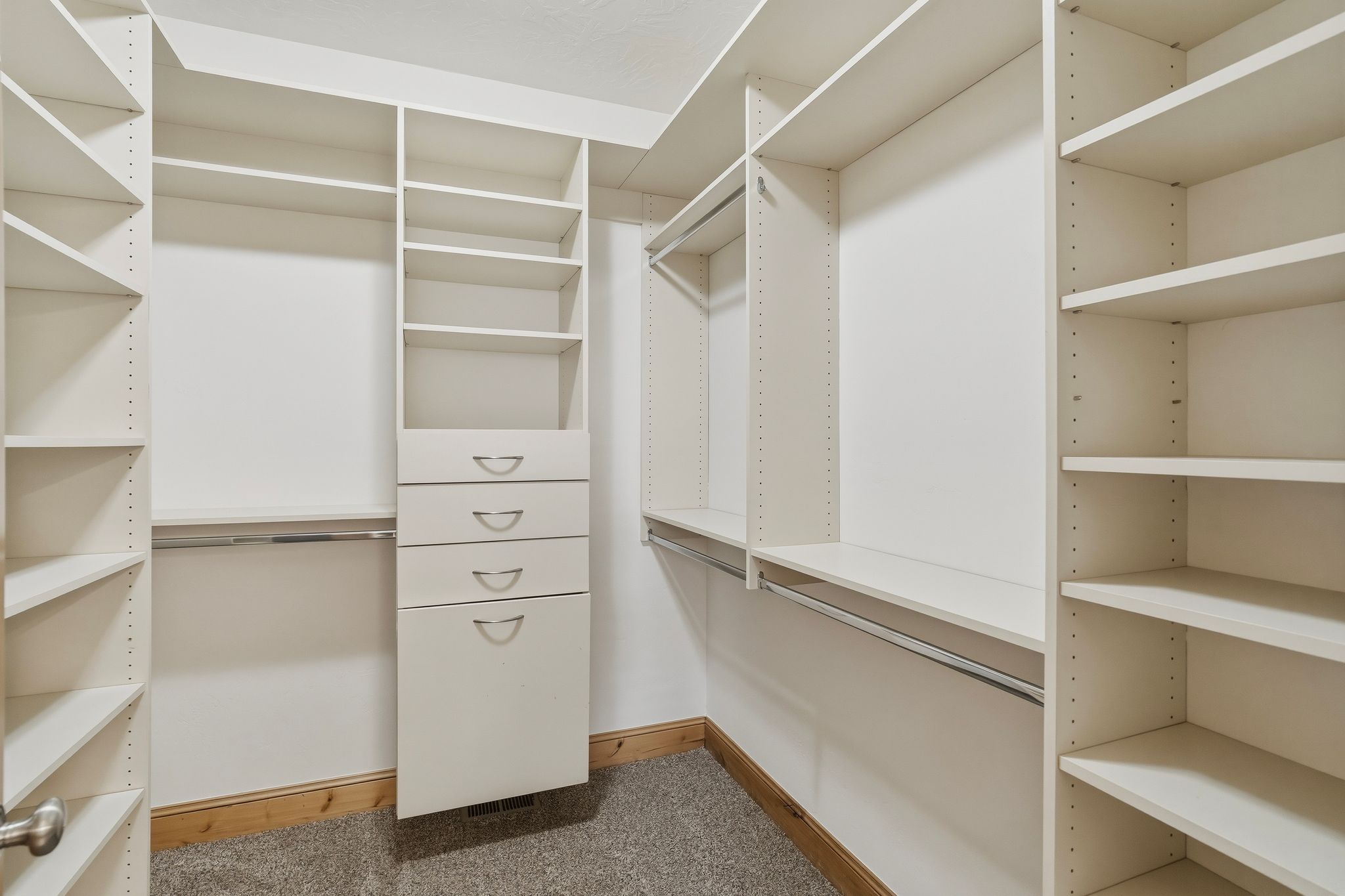 Custom closet system featuring white built-in shelving, hanging rods, and integrated drawers