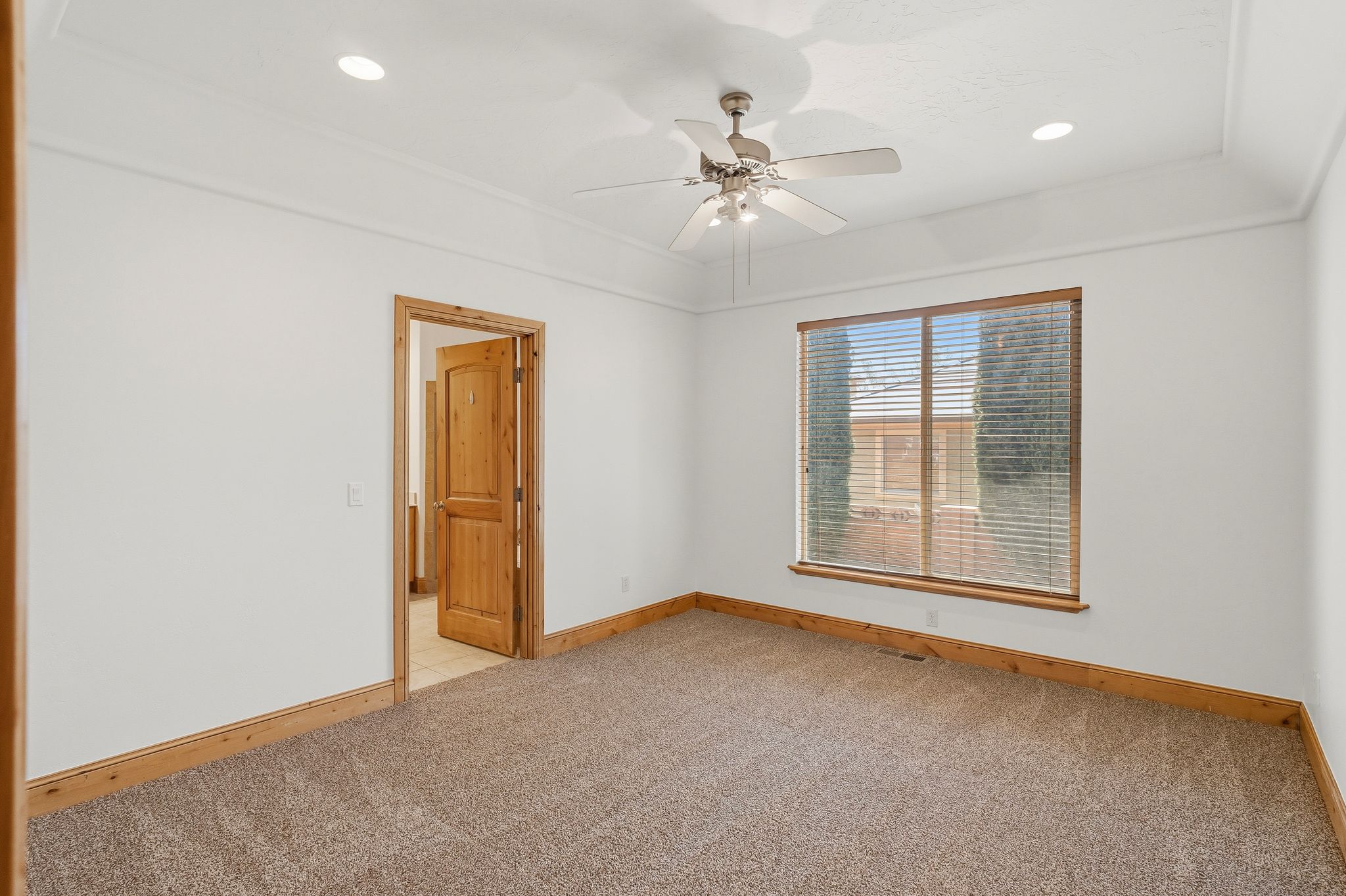 Carpeted room featuring a ceiling fan, recessed lighting, and a tray ceiling