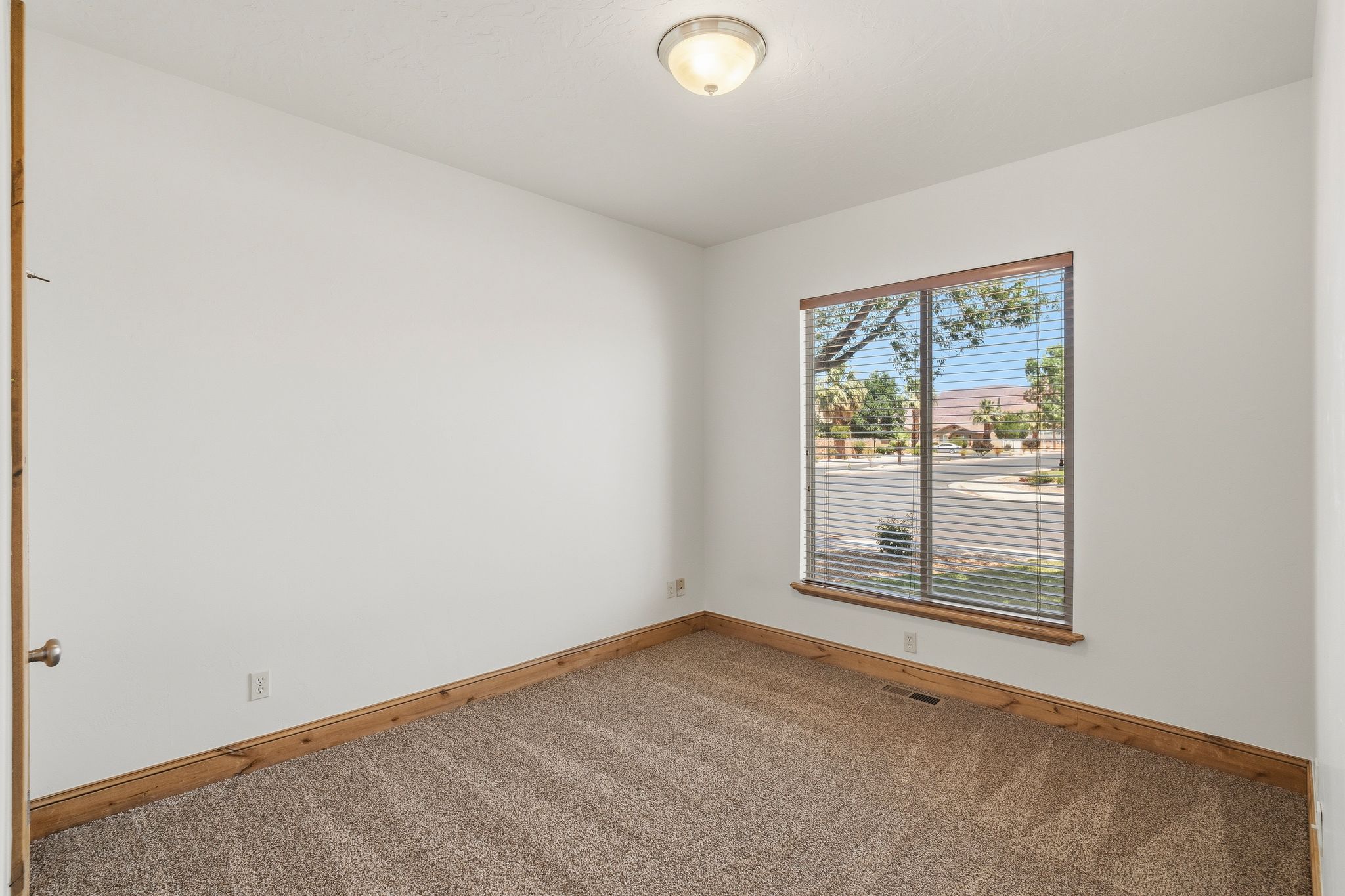 Carpeted room with a single window featuring horizontal blinds