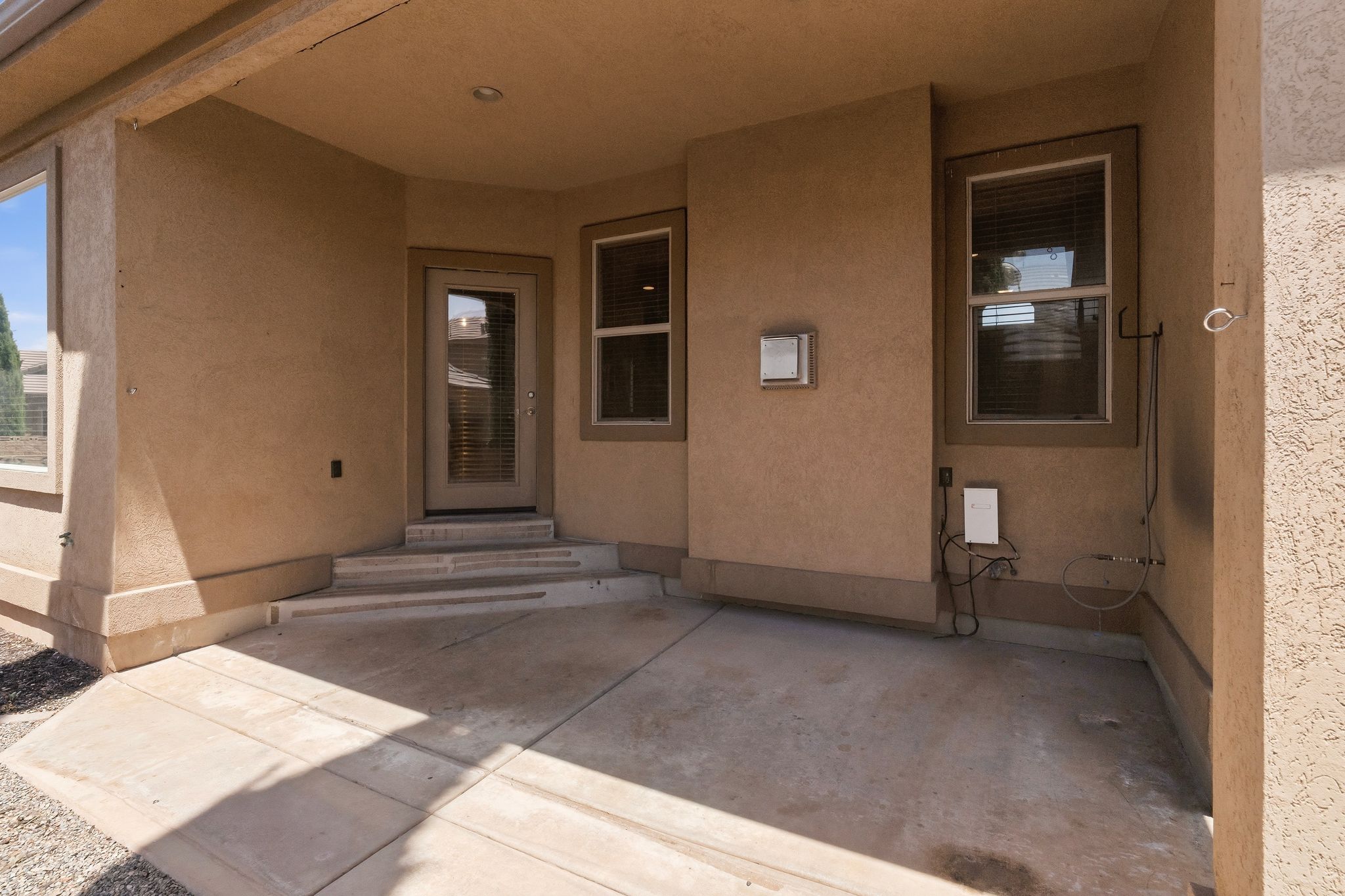 Covered patio area featuring a stucco exterior, concrete flooring, and recessed lighting