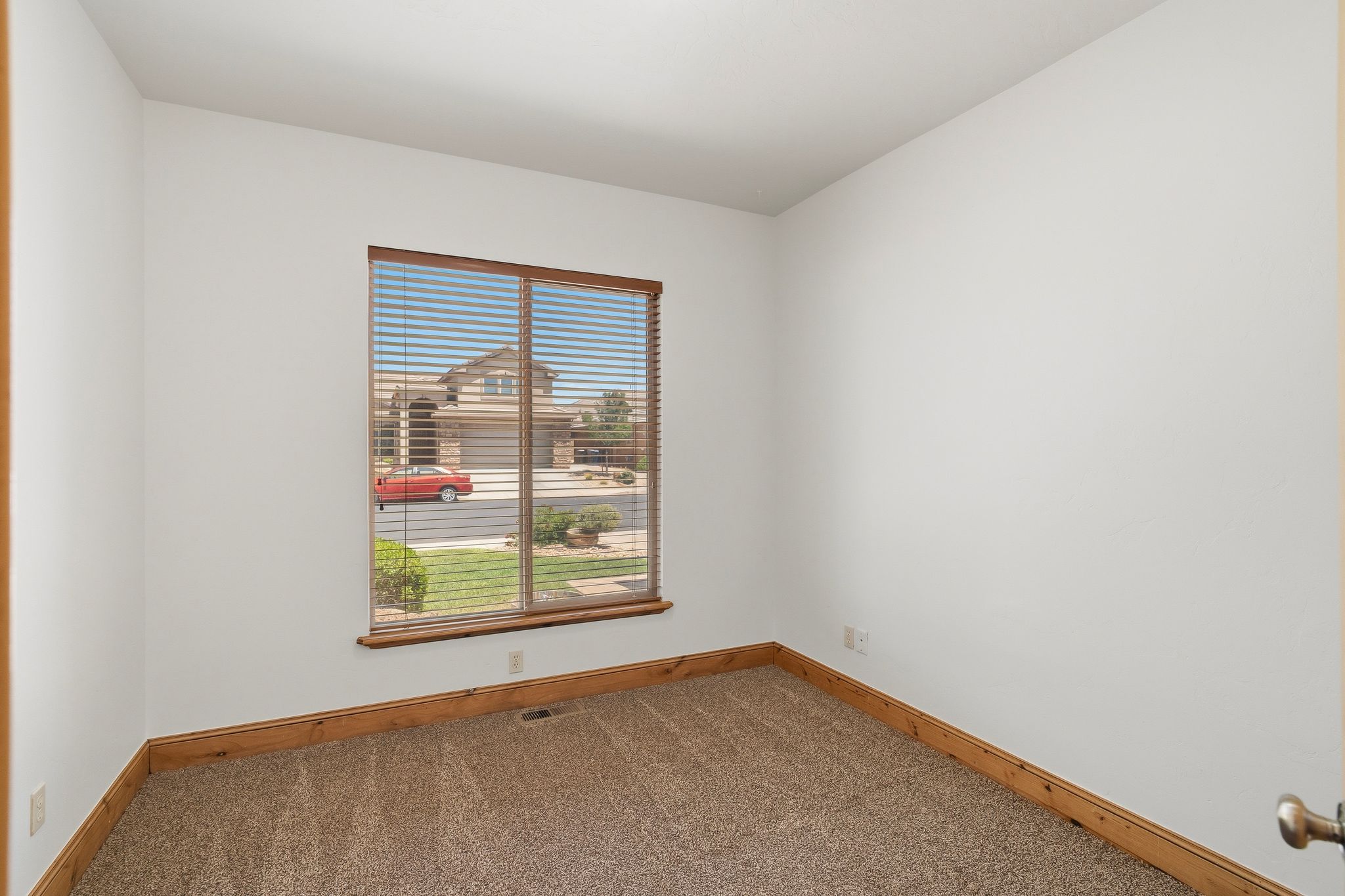 Carpeted room featuring a large window with blinds and wood trim