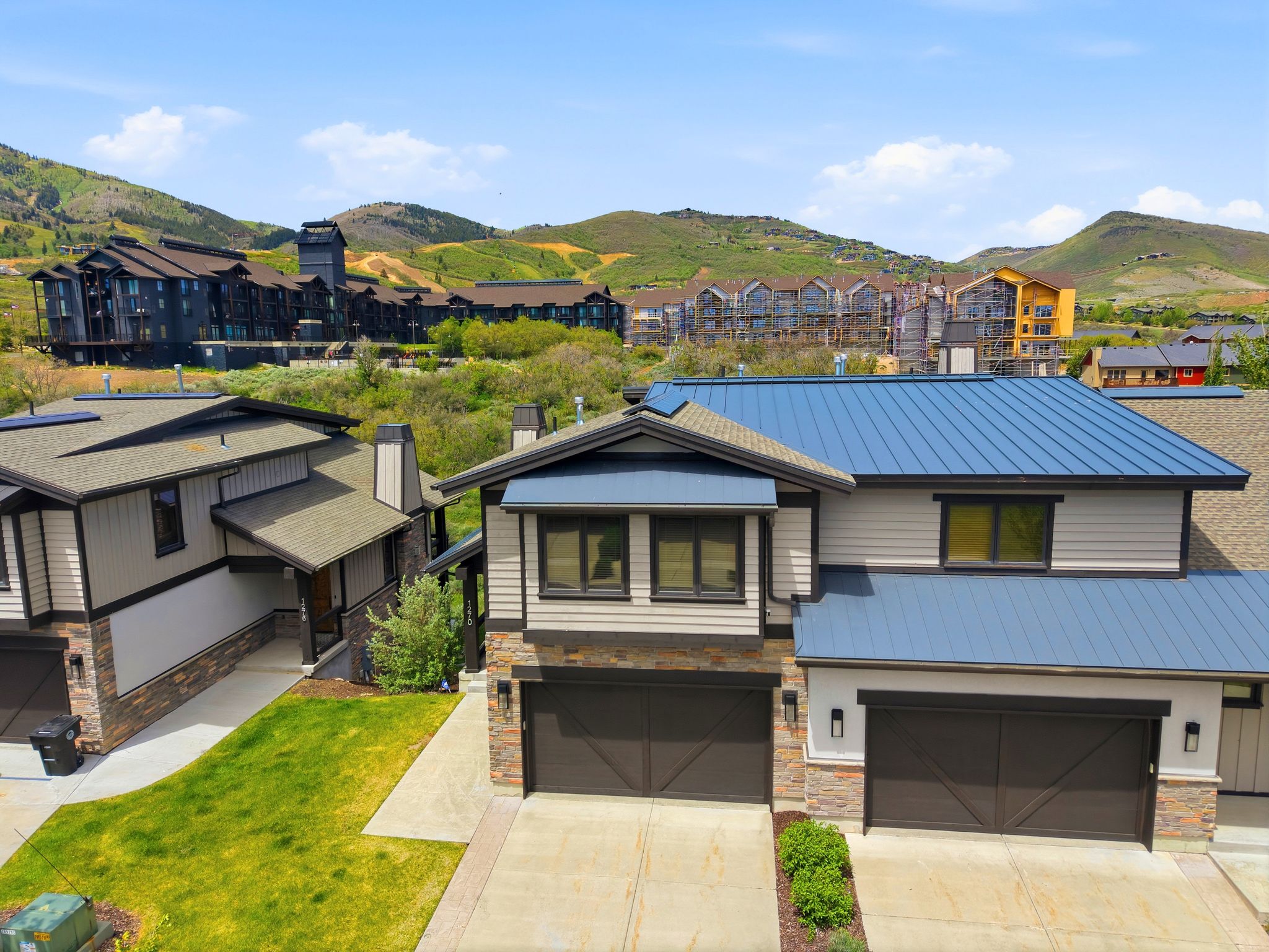 Contemporary exterior featuring a metal roof, stone accents, horizontal siding, and two prominent garage doors
